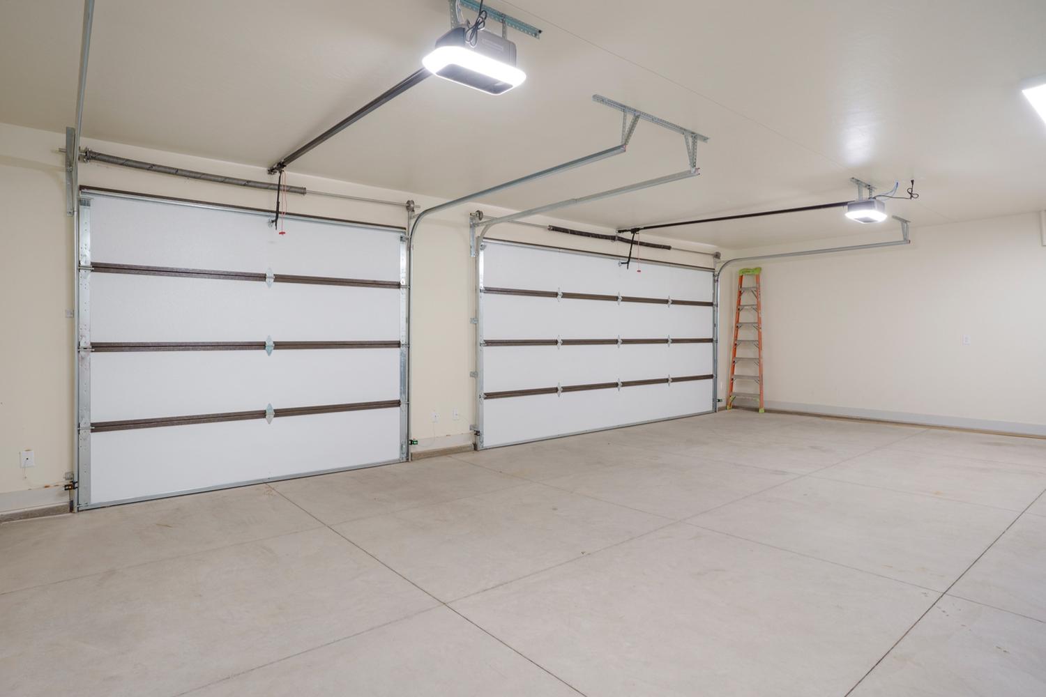 Spacious two-car garage featuring segmented white doors and concrete flooring