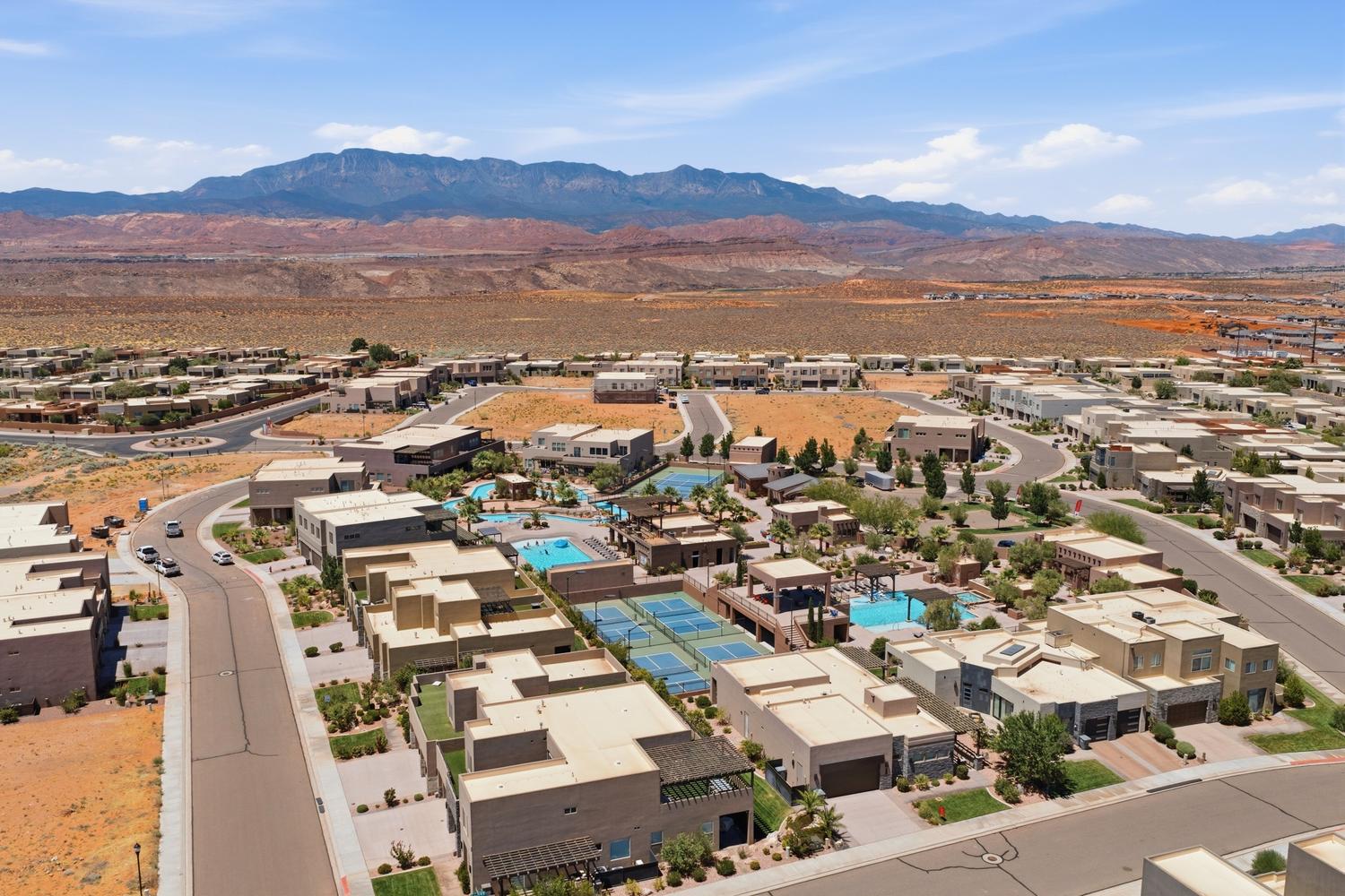 Community featuring multiple residential structures, swimming pools, tennis courts, and a mountainous backdrop