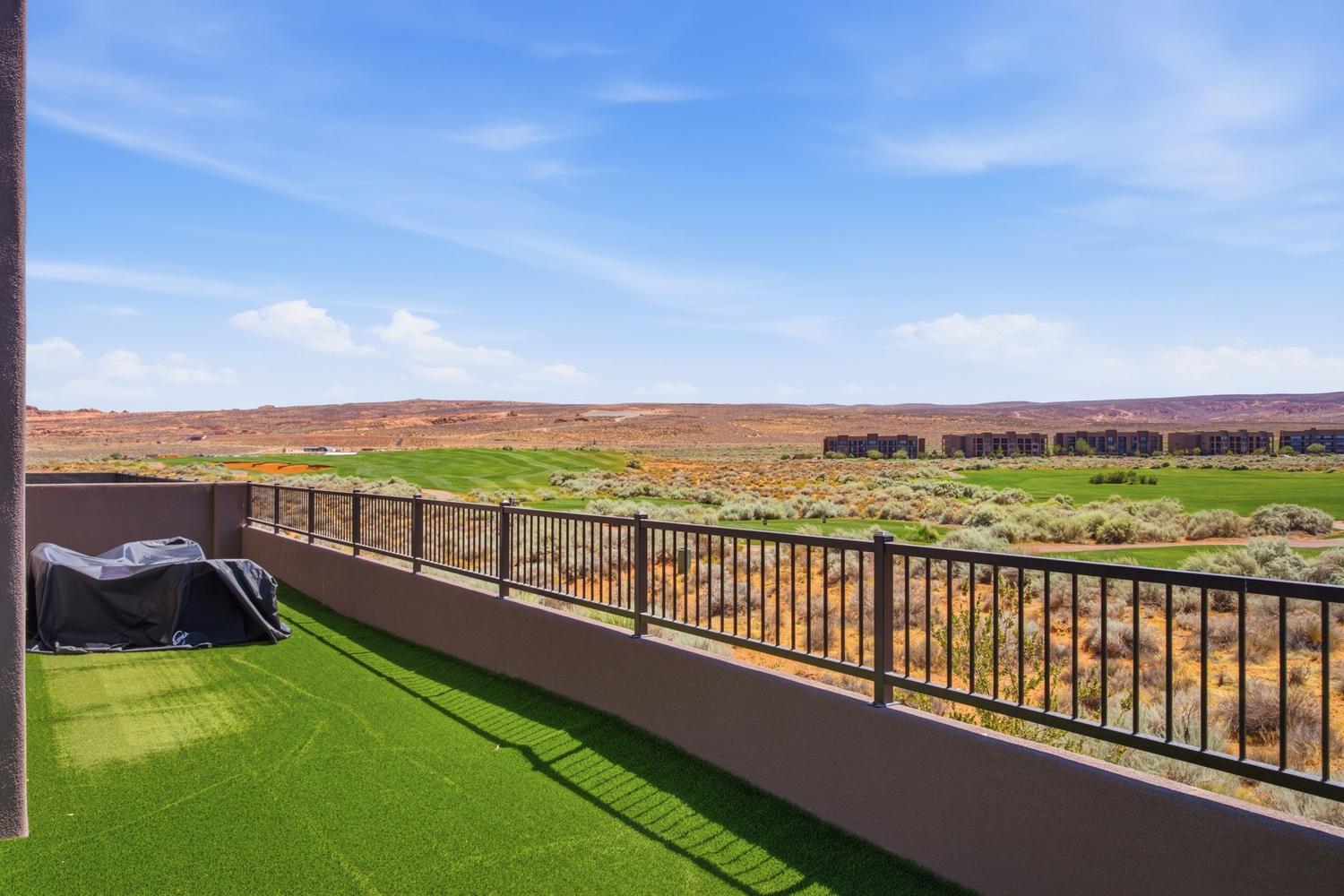 Terrace featuring artificial turf flooring and a dark metal railing