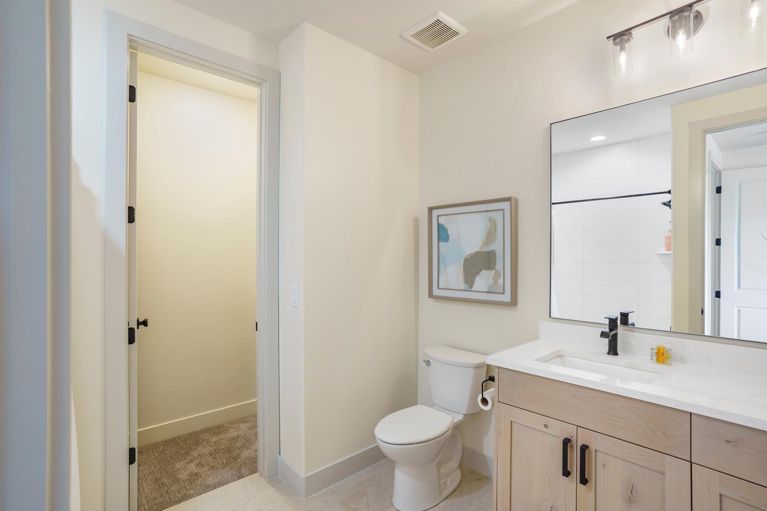 Contemporary bathroom featuring a light wood-finish vanity with dual sinks, white countertop, and rectangular mirror