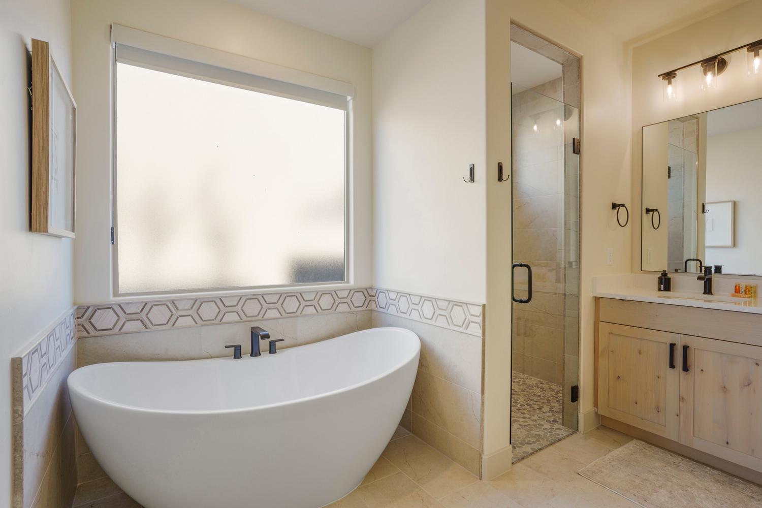 Modern freestanding soaking tub with a frosted privacy window, complemented by a walk-in shower with a glass enclosure and pebble floor