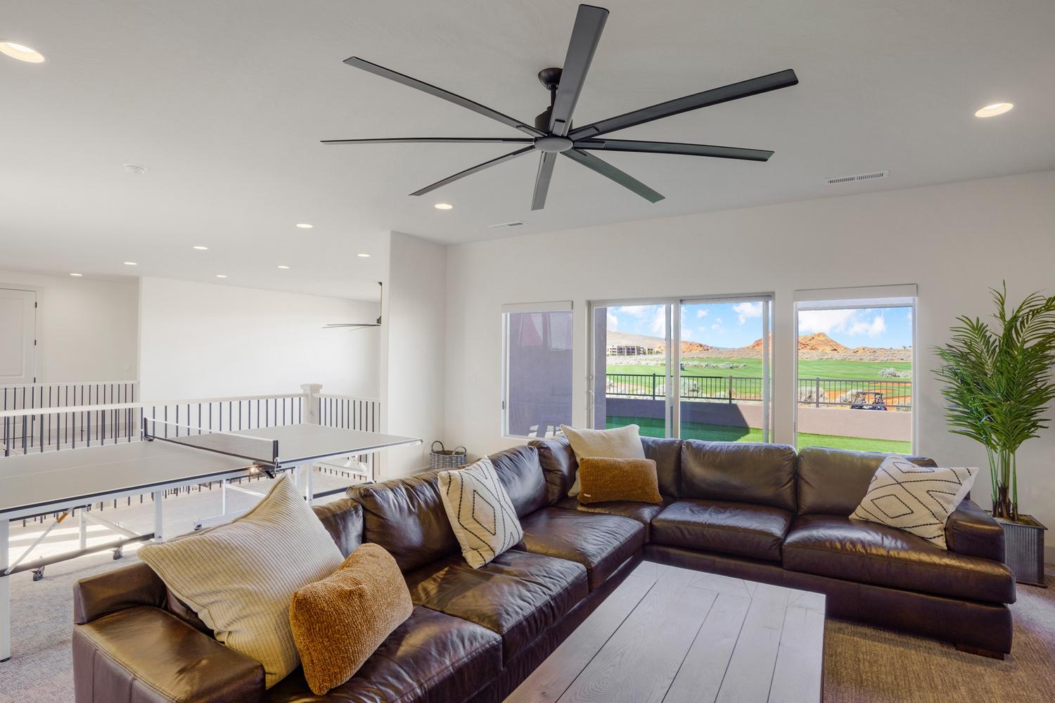 Spacious entertainment area featuring an expansive ceiling fan, recessed lighting, and large sliding glass doors