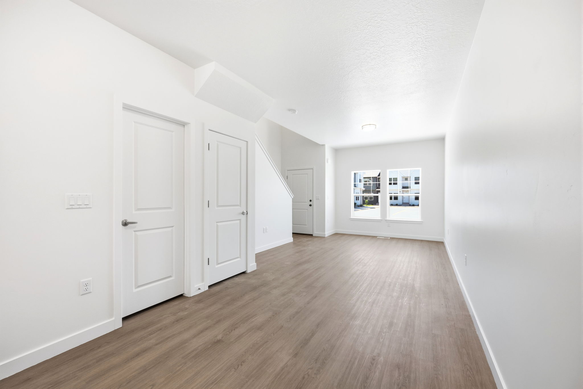 Open-concept interior featuring light wood-finish flooring, white walls, and bright overhead lighting