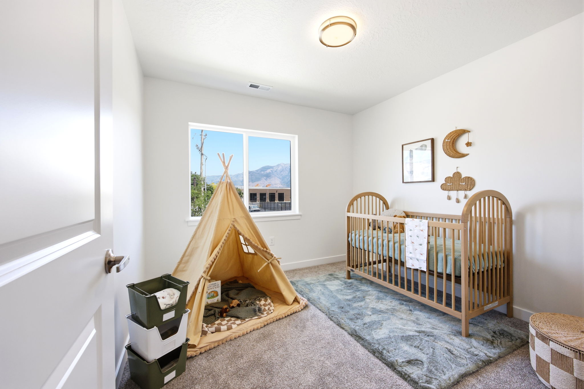 Neutral-toned room featuring a window with a mountain backdrop, plush carpet flooring, white walls, and a contemporary flush-mount ceiling light