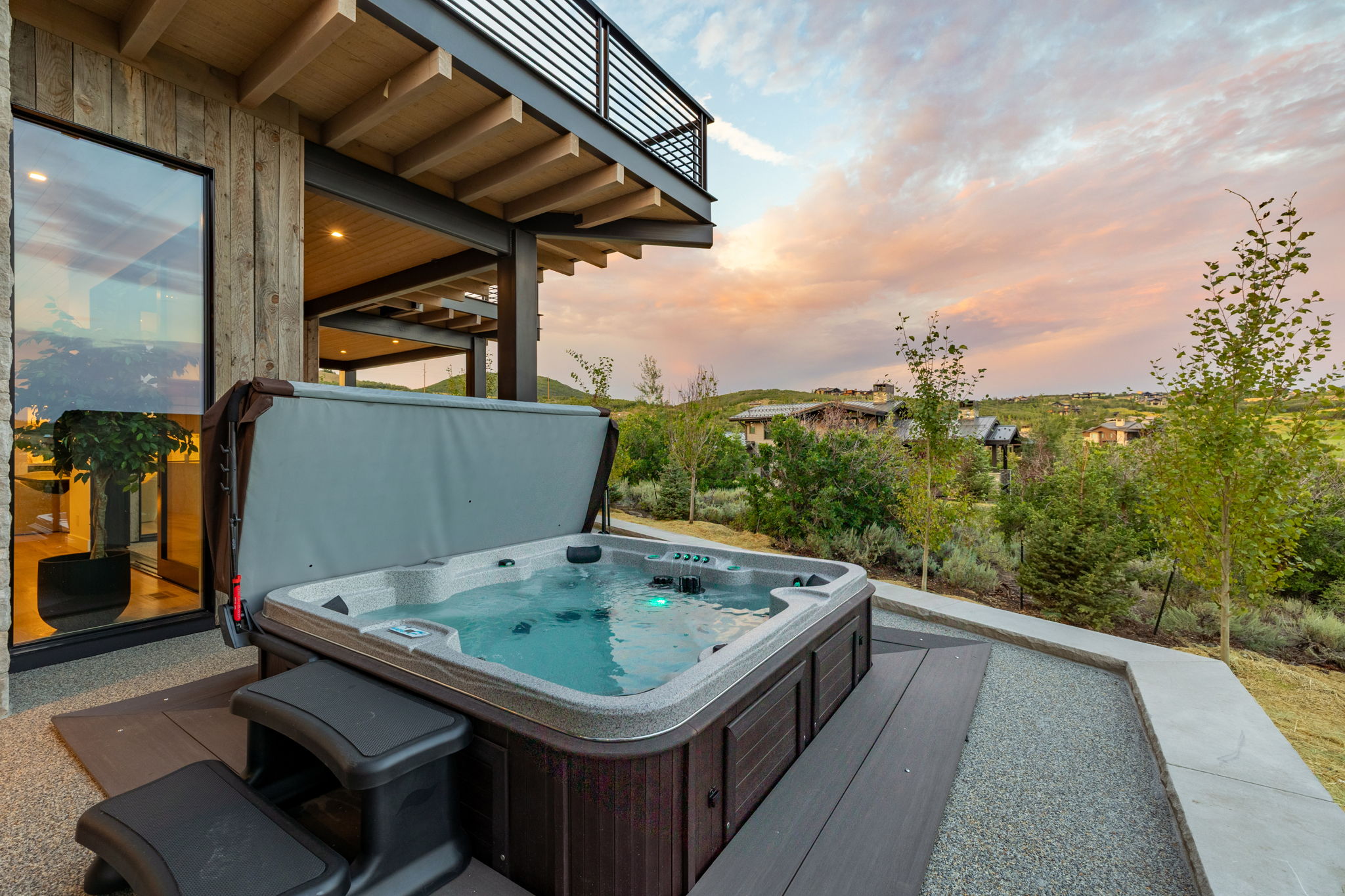Outdoor hot tub featuring integrated steps on a patio with gravel and wood-finish decking