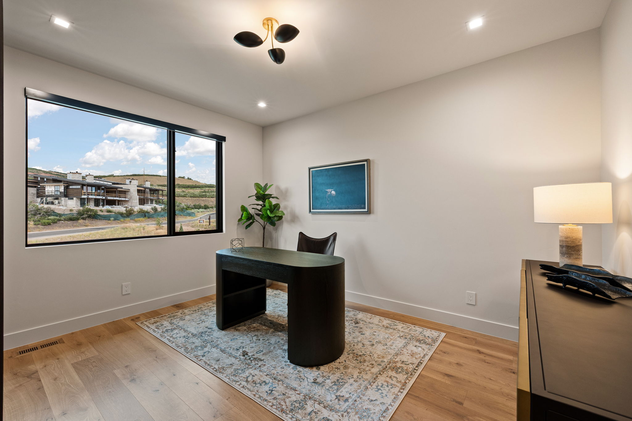 Room featuring a large window with black trim, light wood-finish flooring, recessed lighting, and a modern ceiling fixture