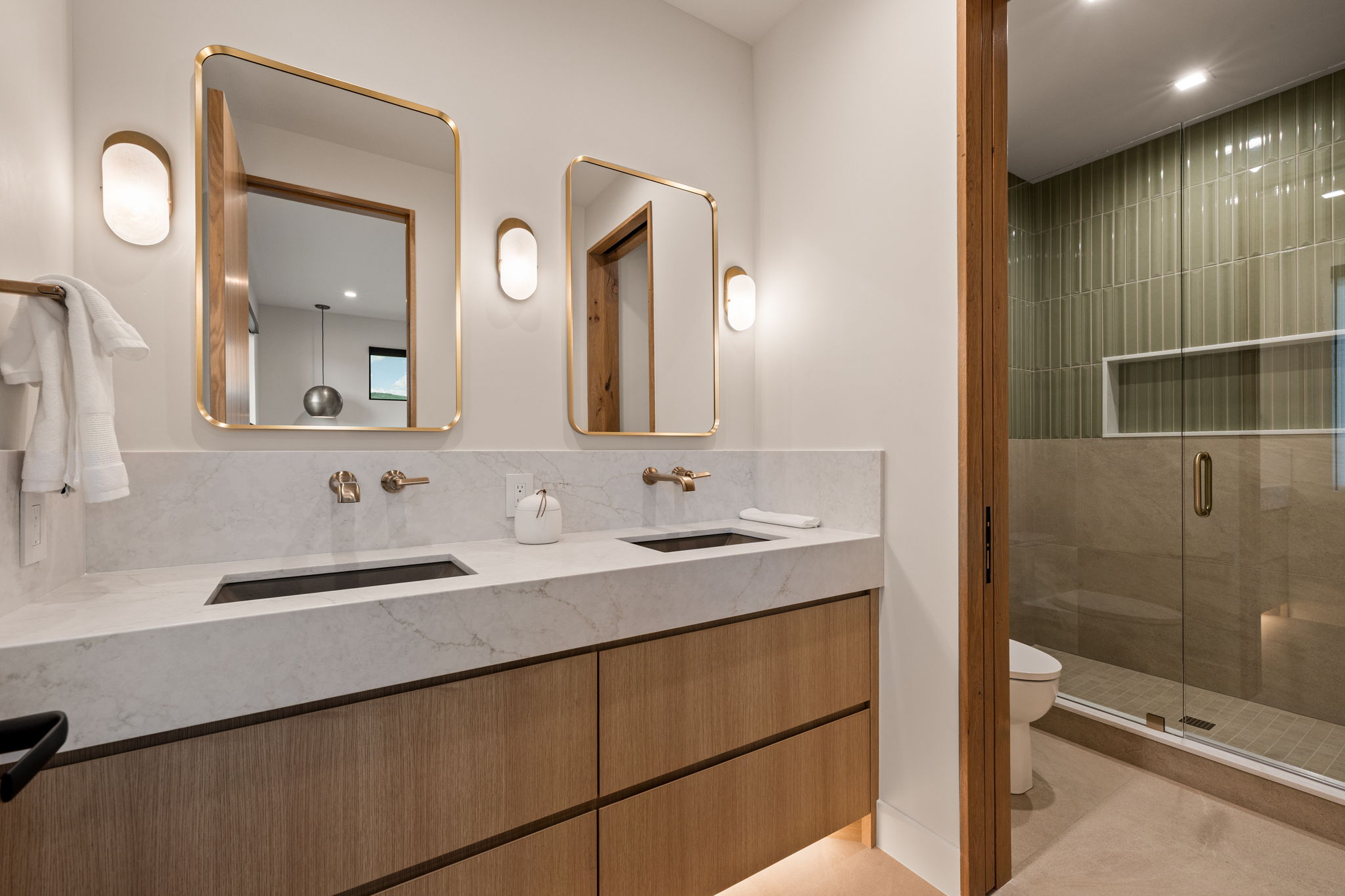 Dual vanity with integrated rectangular sinks, wall-mounted brass faucets, and quartz countertop