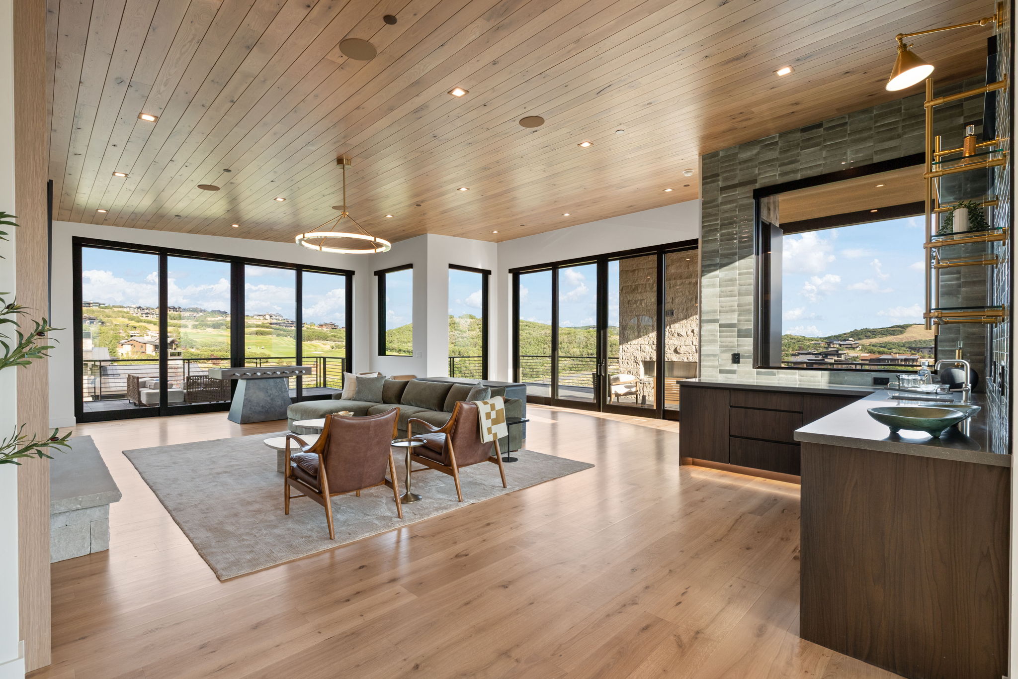 Spacious interior featuring wood-finish flooring, a wood-paneled ceiling with recessed lighting, and expansive sliding glass doors