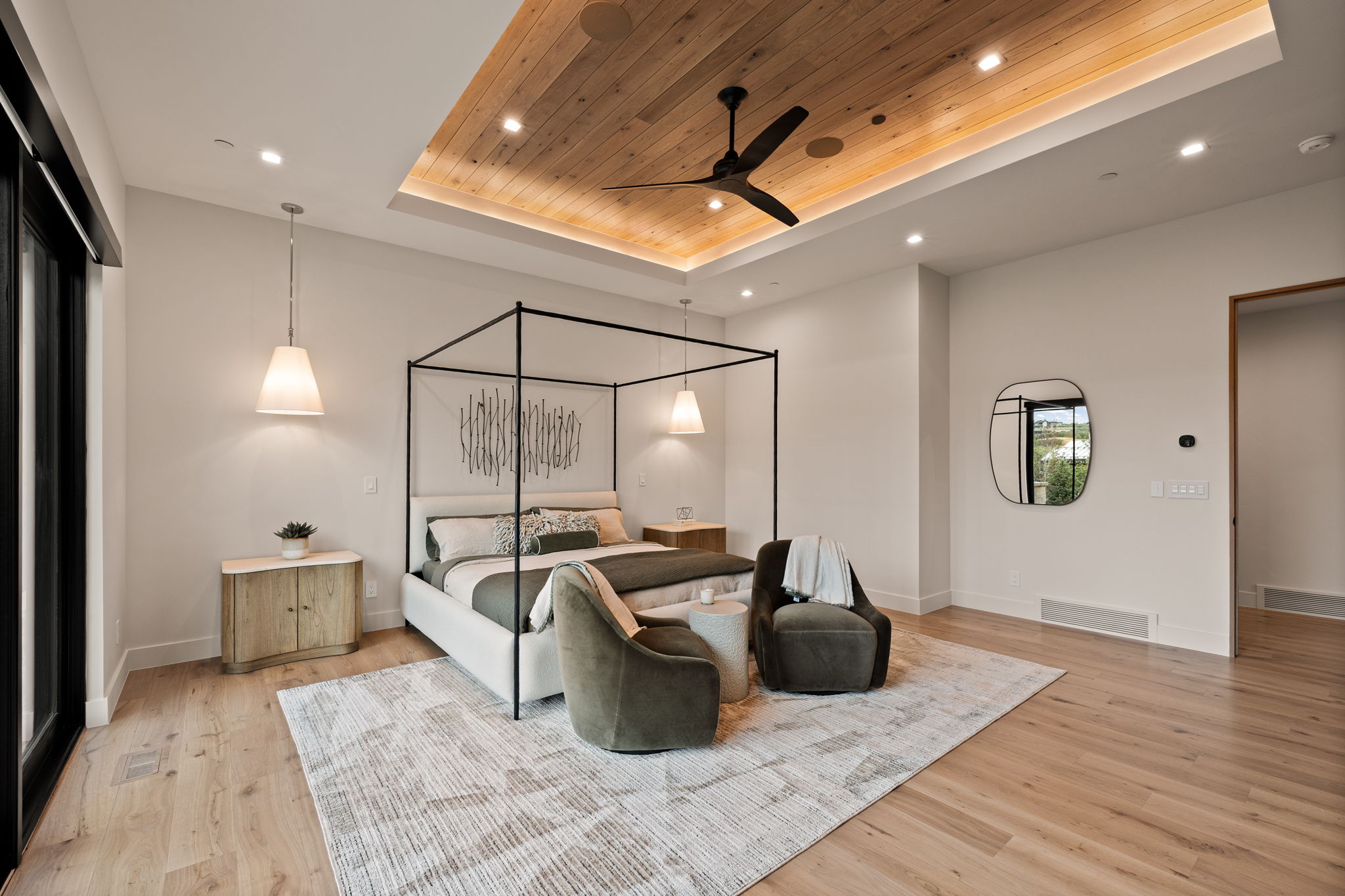 Spacious room featuring wood-finish flooring, a tray ceiling with recessed lighting and a ceiling fan, and a large glass door
