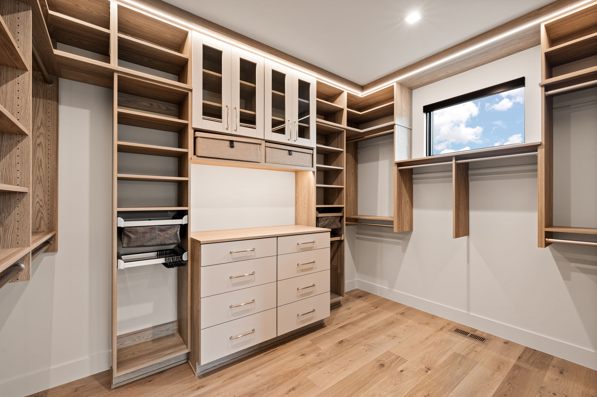 Custom closet system featuring varied storage options, wood-finish flooring, recessed lighting, built-in shelving, and drawers with brushed nickel hardware