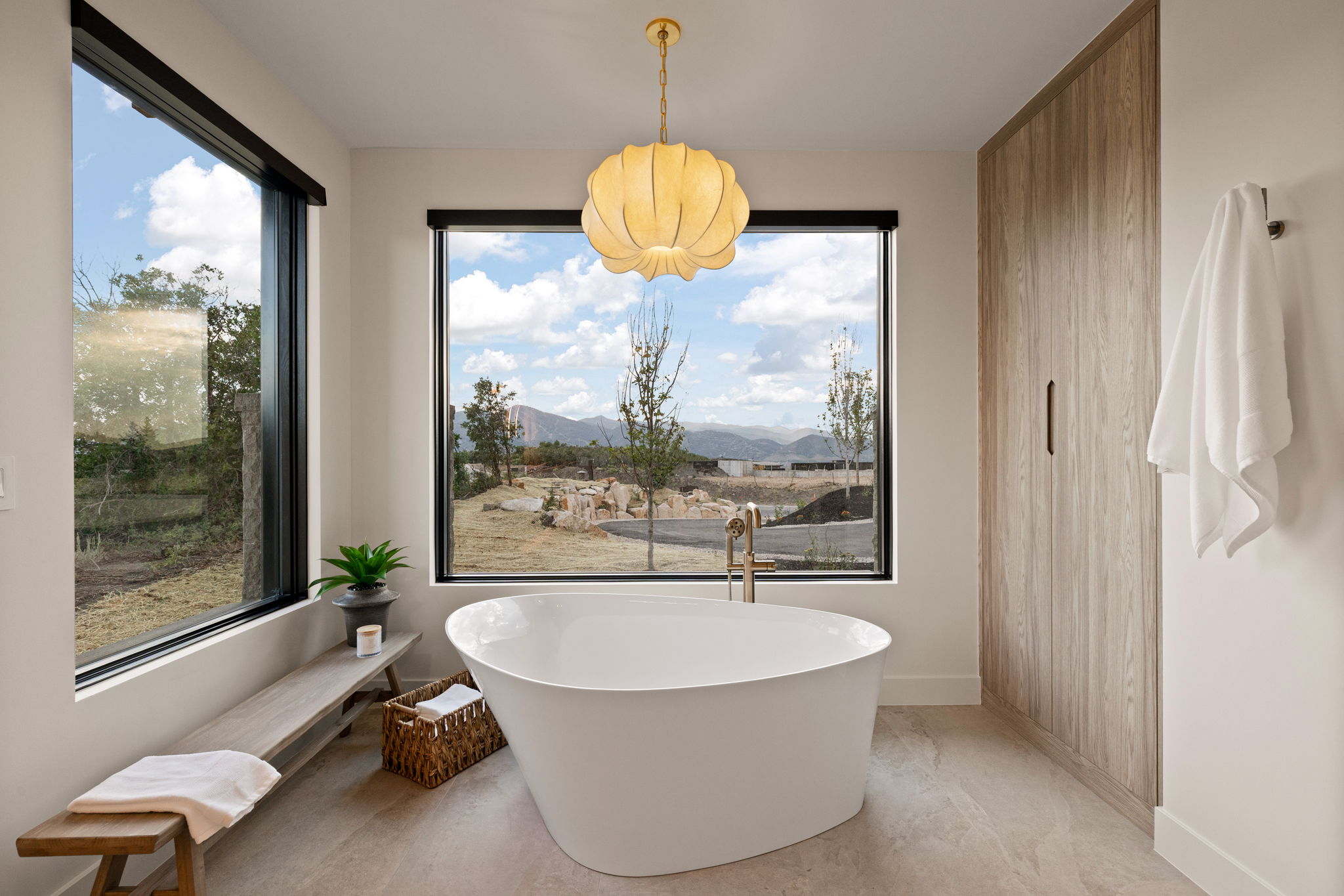 Freestanding soaking tub centered beneath a large picture window