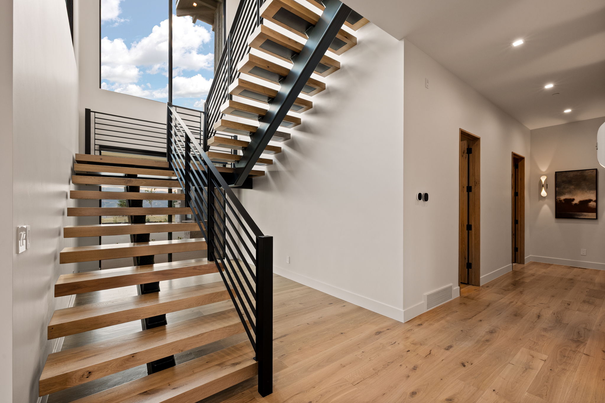 Open-tread staircase with wood-finish steps and black metal railings