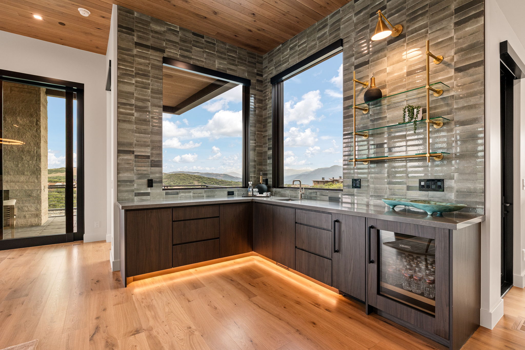 Built-in wet bar featuring dark wood cabinetry, a beverage refrigerator, and a tiled backsplash