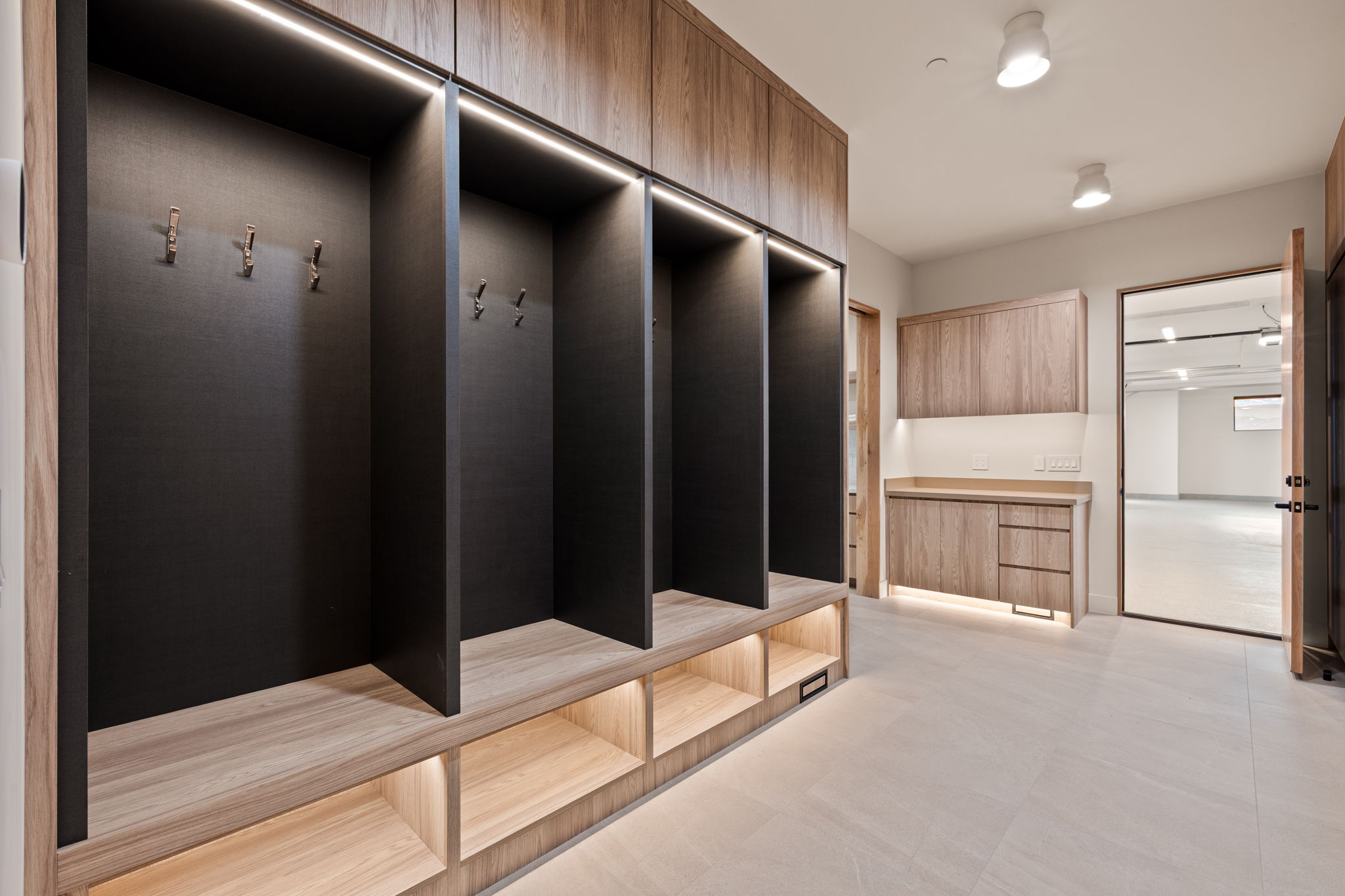 Built-in storage solutions featuring wood-finish cabinetry, integrated lighting, and metal coat hooks