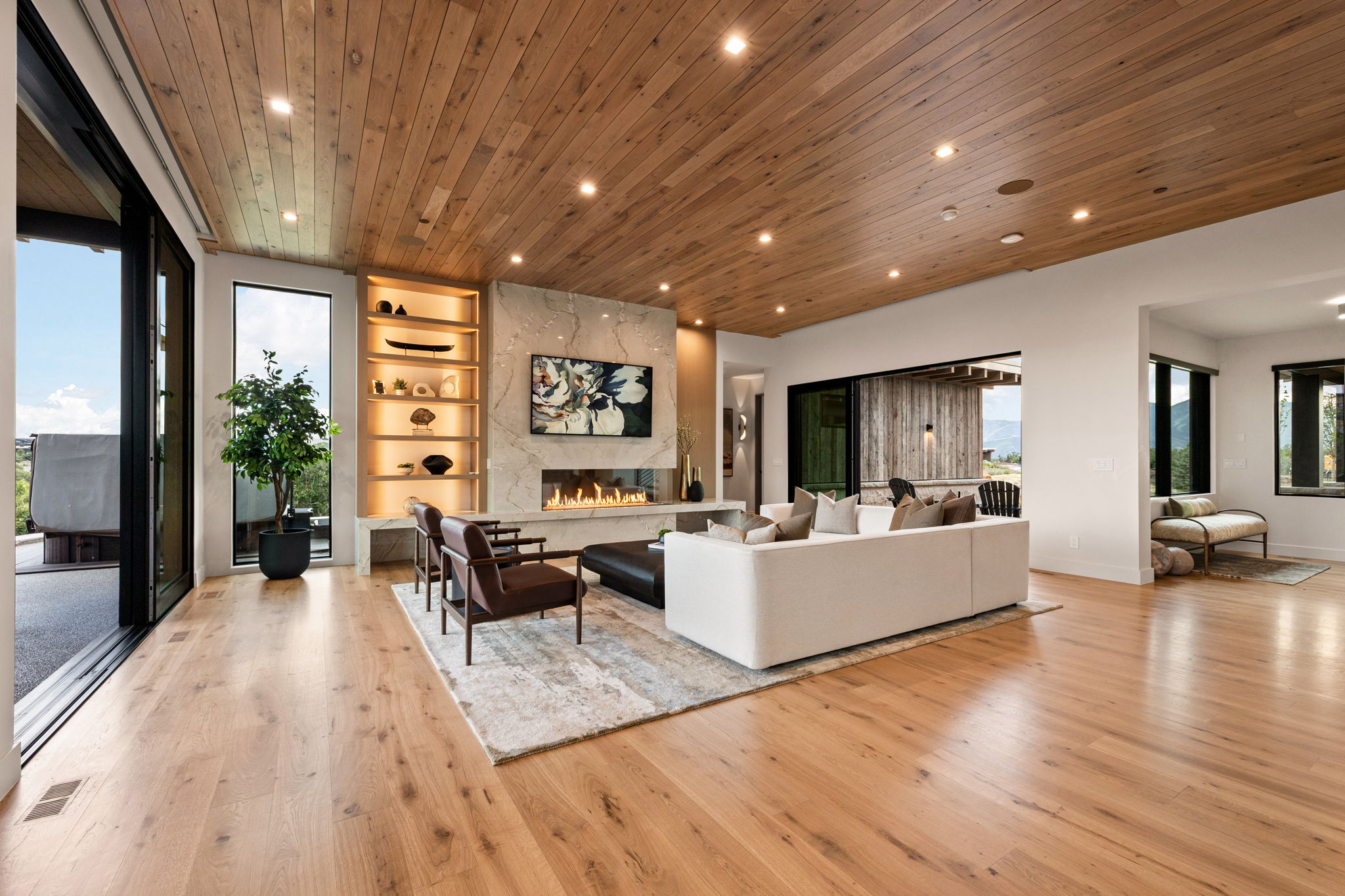 Spacious living area featuring wide plank wood-finish flooring and a matching wood-paneled ceiling with recessed lighting