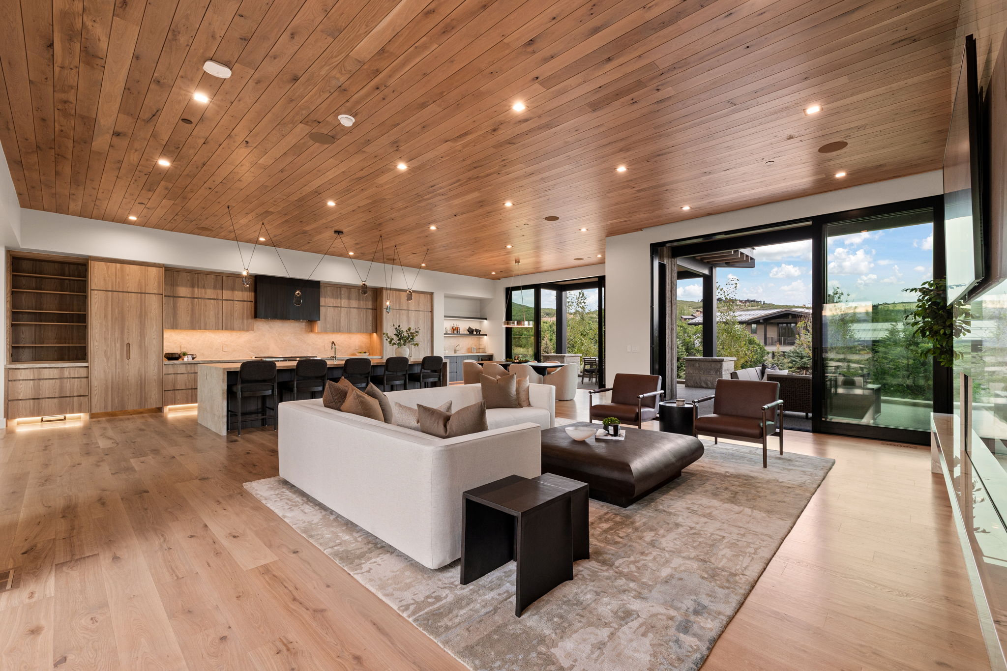 Open-concept living space with wood-finish flooring and a matching paneled ceiling
