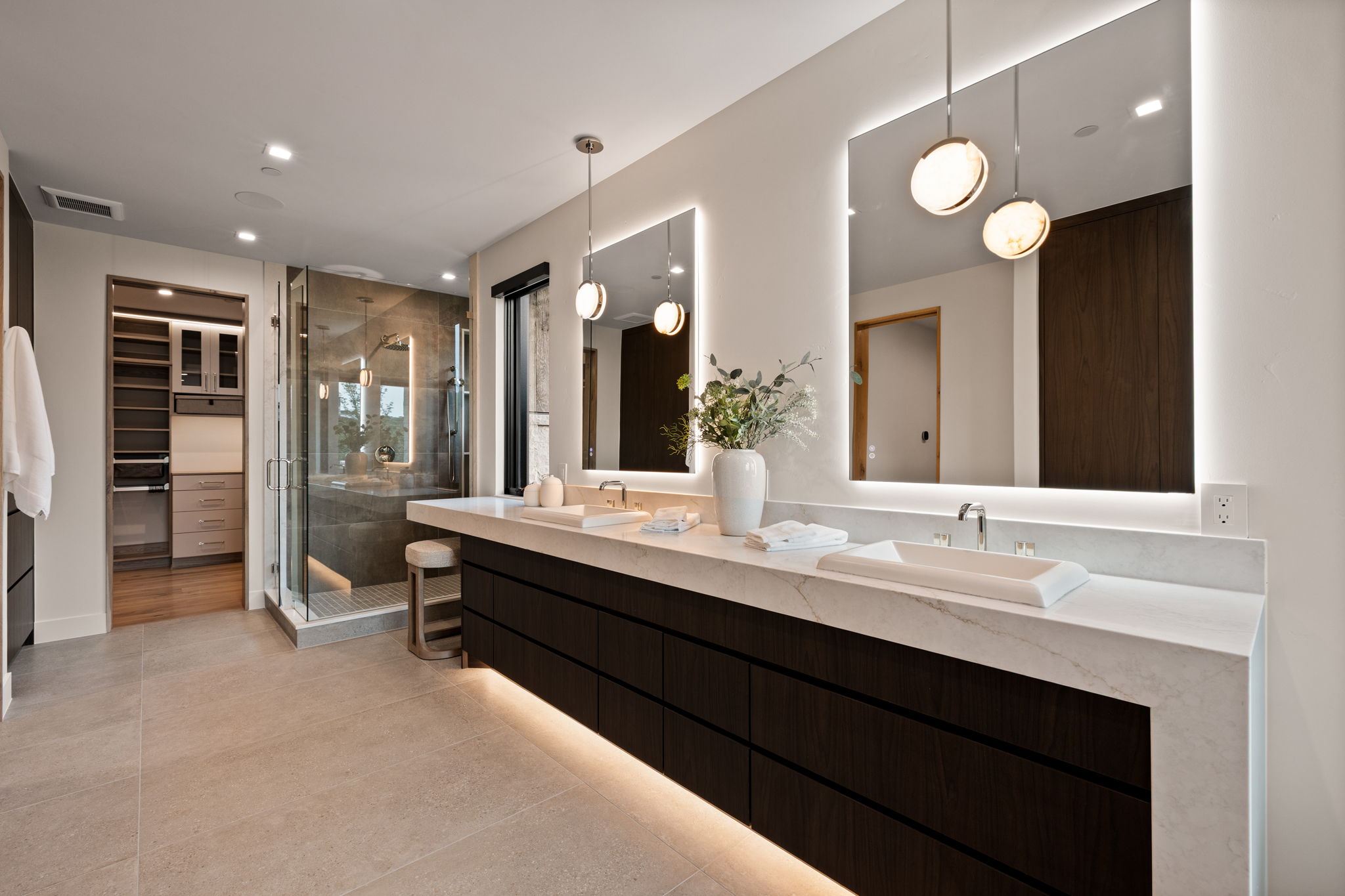 Modern bathroom featuring a dual vanity with vessel sinks, white stone countertops, and dark wood-finish cabinetry