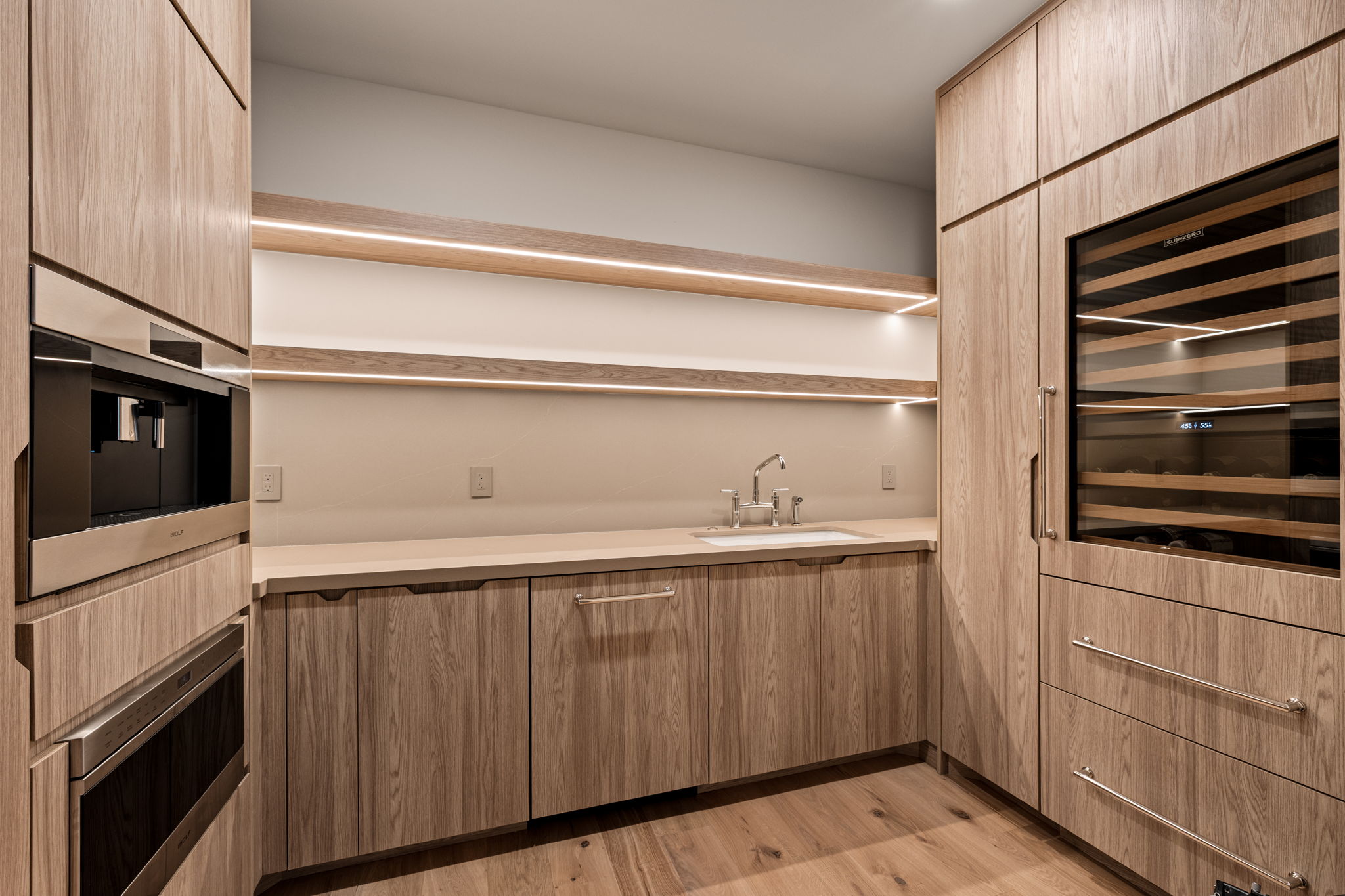 Built-in beverage station featuring a wine refrigerator, integrated coffee system, and a separate oven