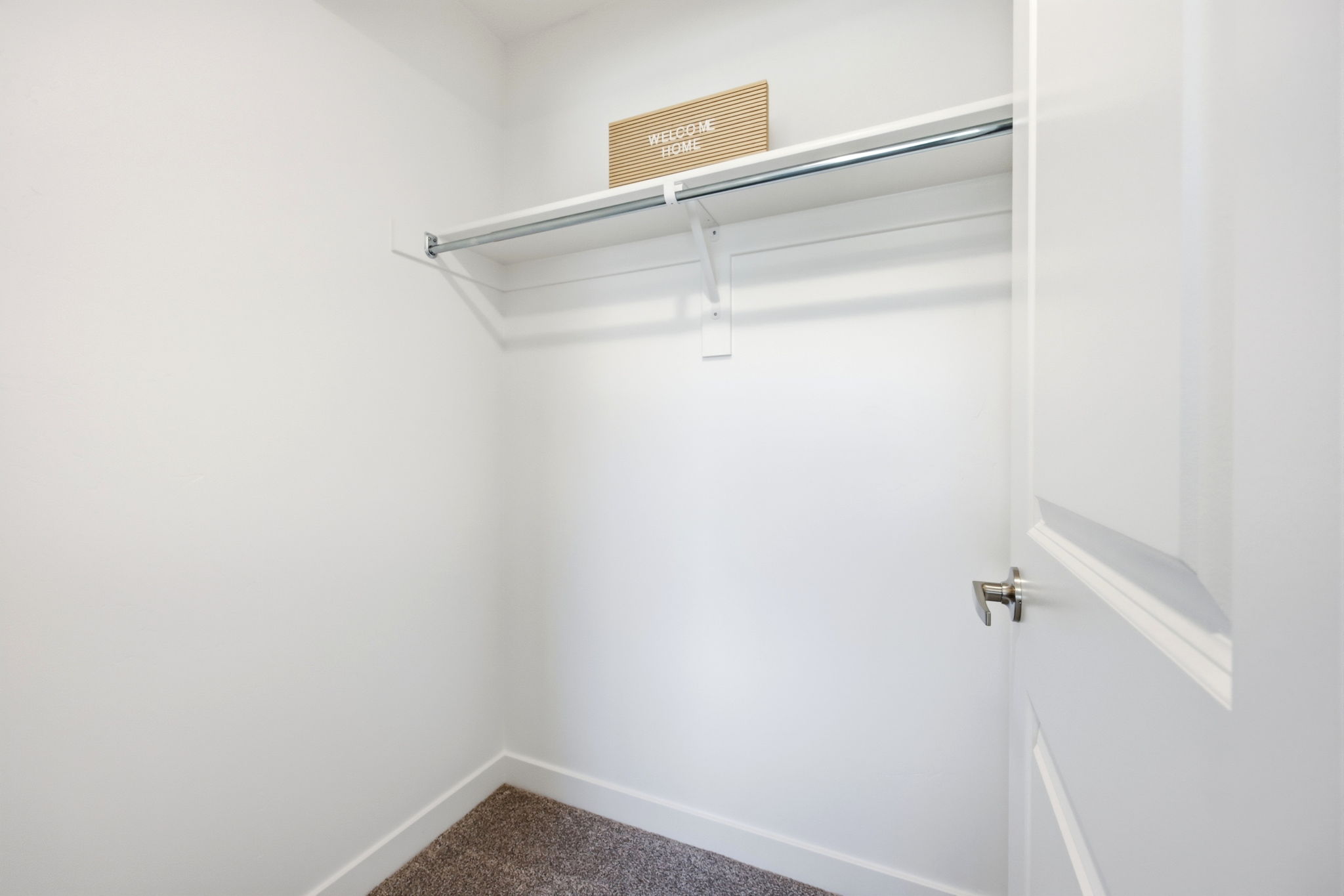 Interior closet featuring a built-in shelf and clothing rod, white walls, and carpeting