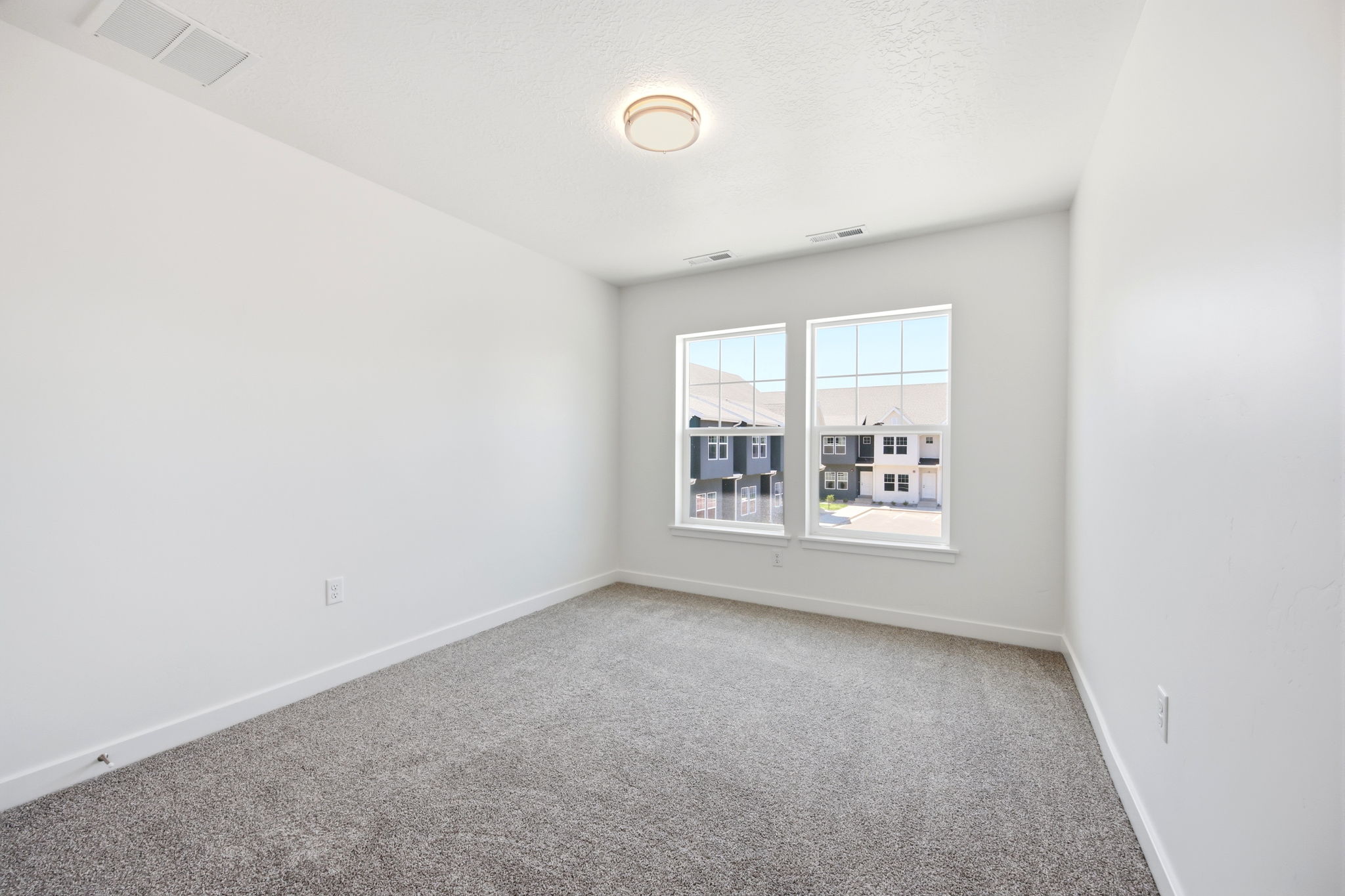 Bright room featuring two large windows, neutral gray carpet, white walls, white trim, and a contemporary ceiling light fixture