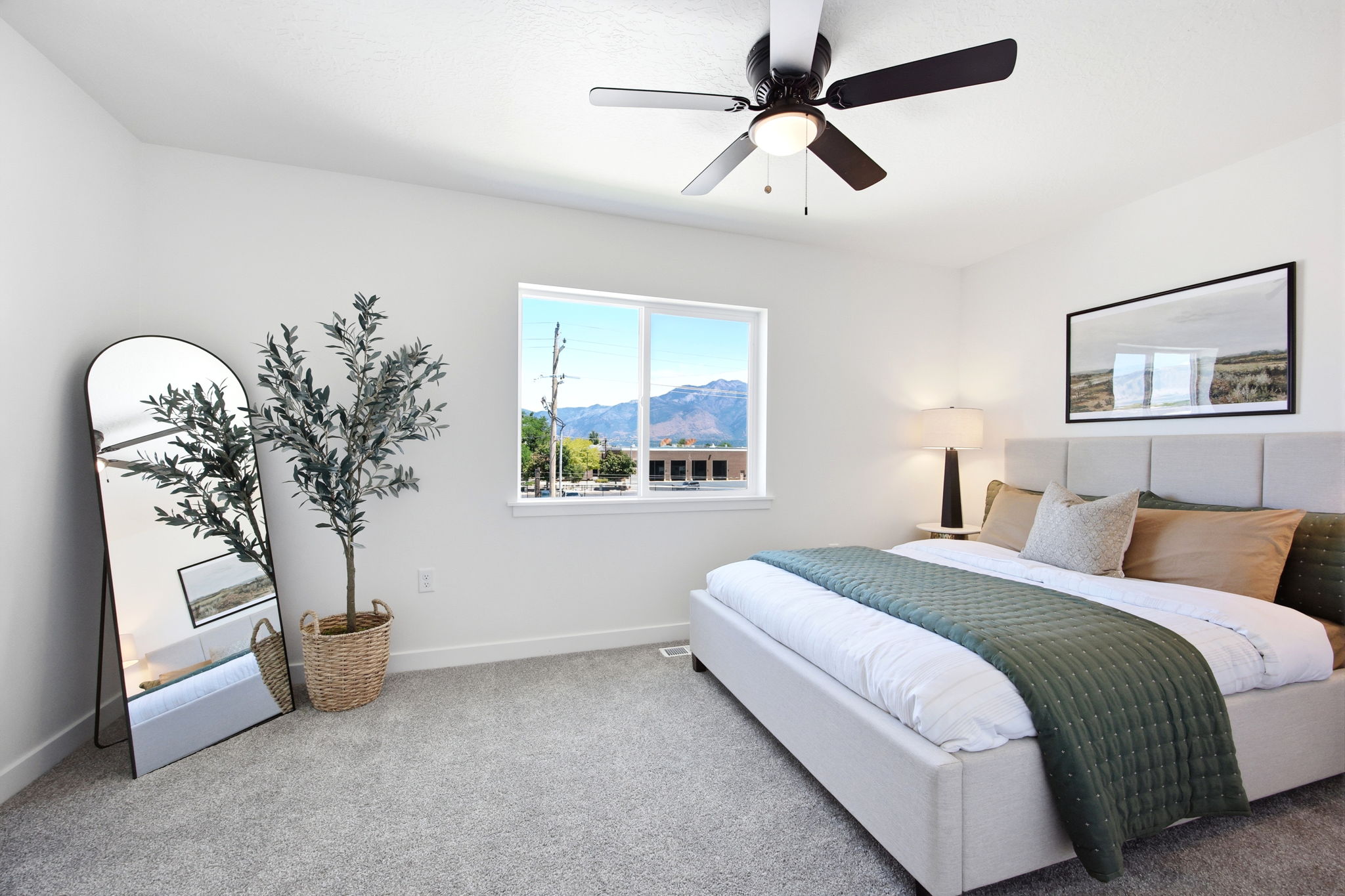 Spacious room featuring a large window, neutral wall tones, textured carpeting, and a ceiling fan with integrated lighting