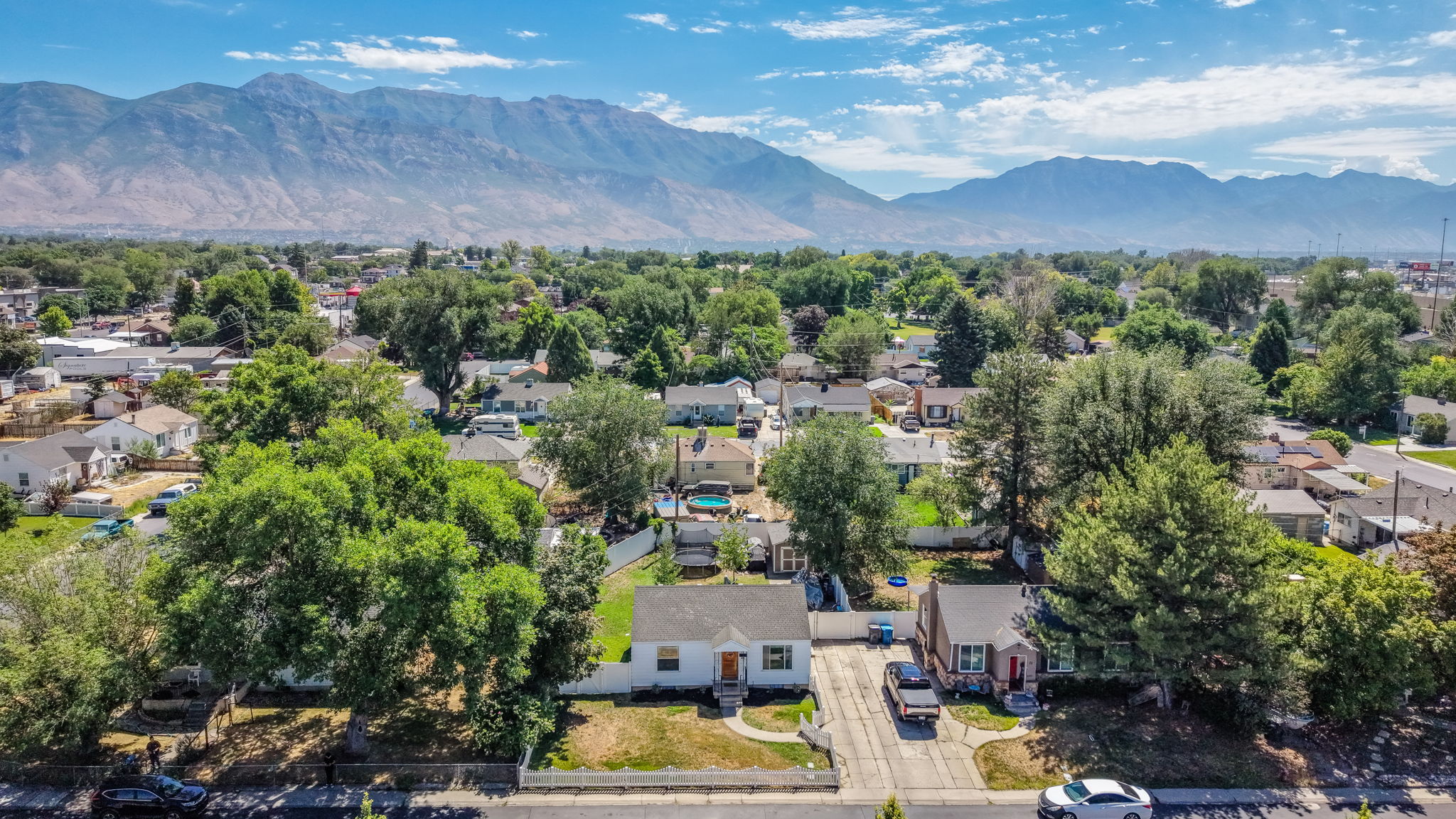 Expansive aerial view showcasing a neighborhood with mature trees and mountain scenery