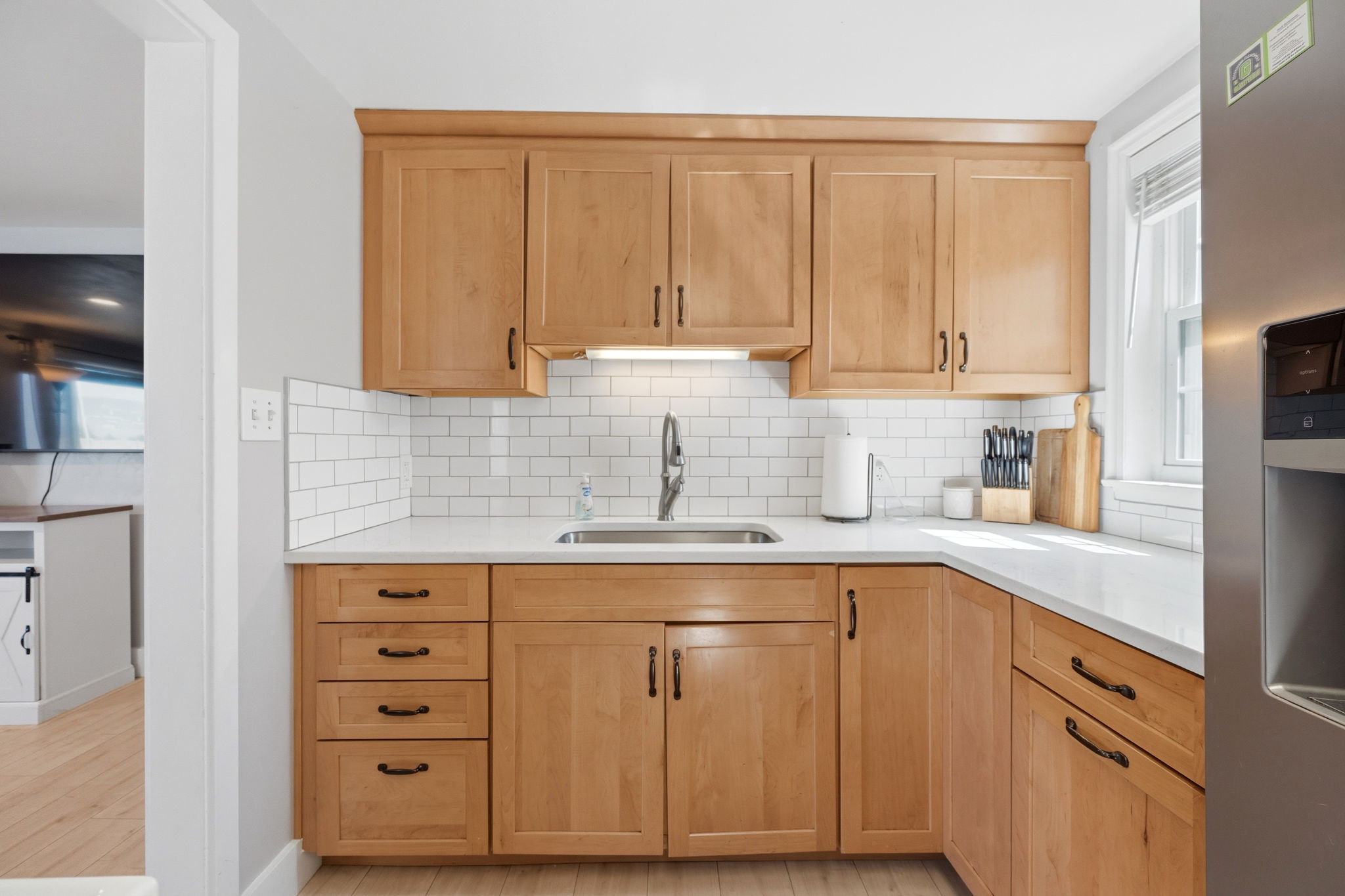 Kitchen featuring natural wood-finish cabinetry, white subway tile backsplash, and light-toned countertops