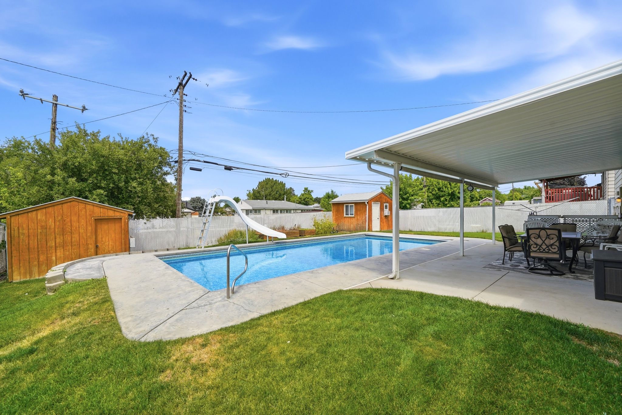 In-ground swimming pool with a white slide, surrounded by a concrete patio