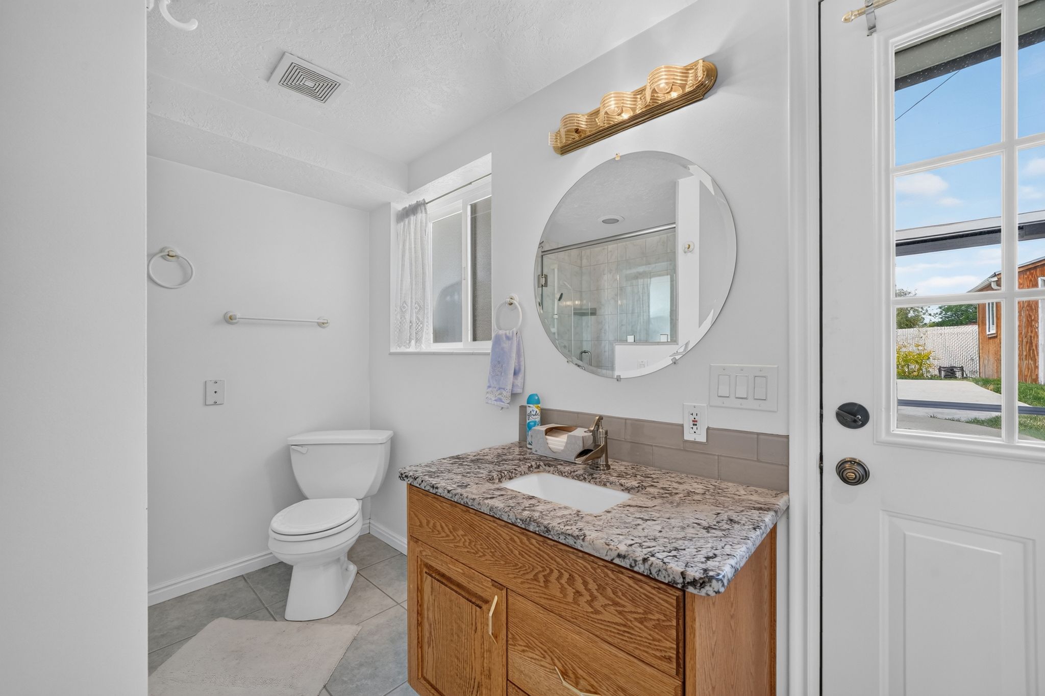 Bathroom featuring a wood-finish vanity with a speckled countertop and an integrated sink, illuminated by a decorative light fixture
