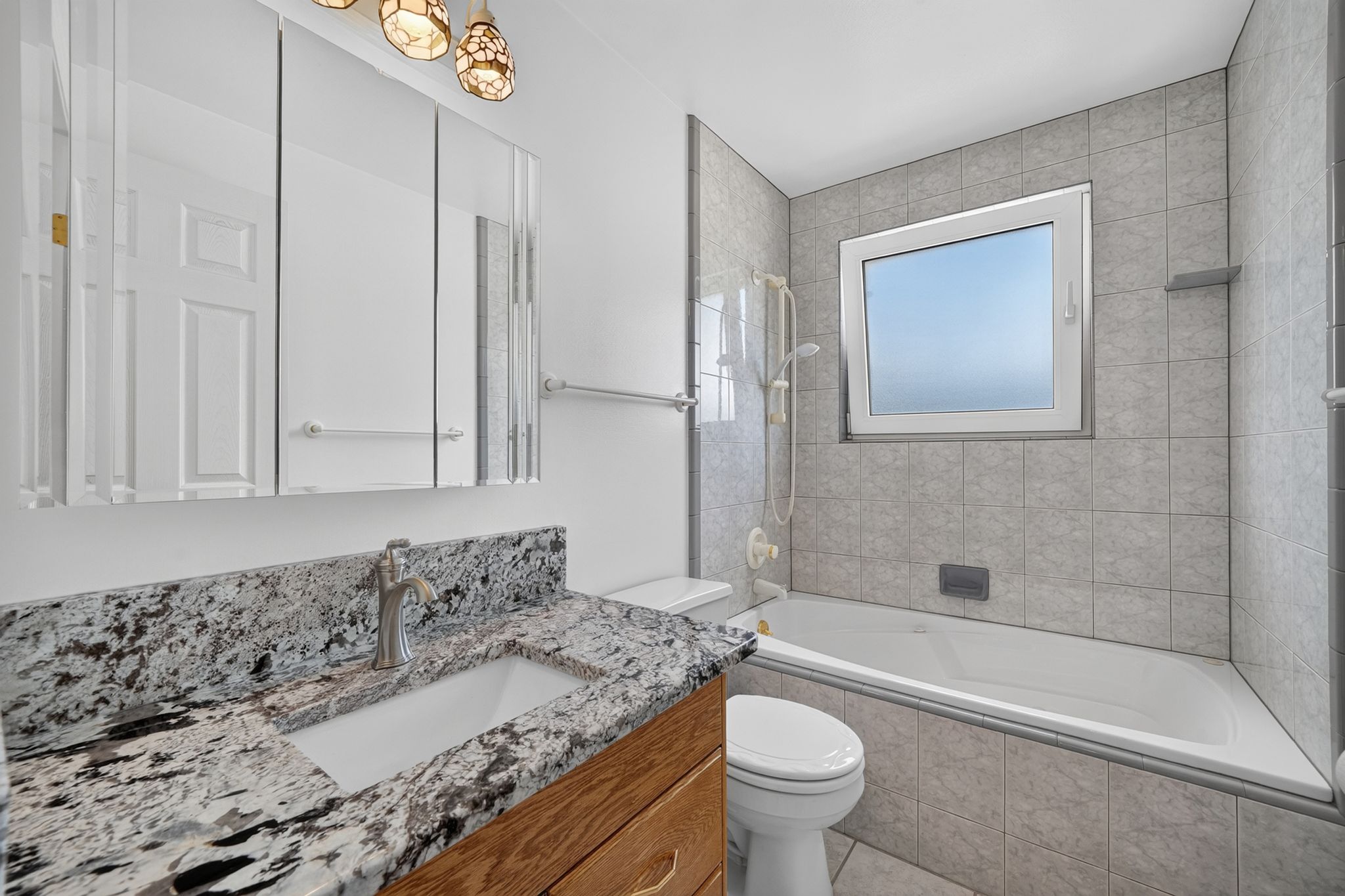 Bathroom featuring a white bathtub, tiled shower surround, and an integrated window