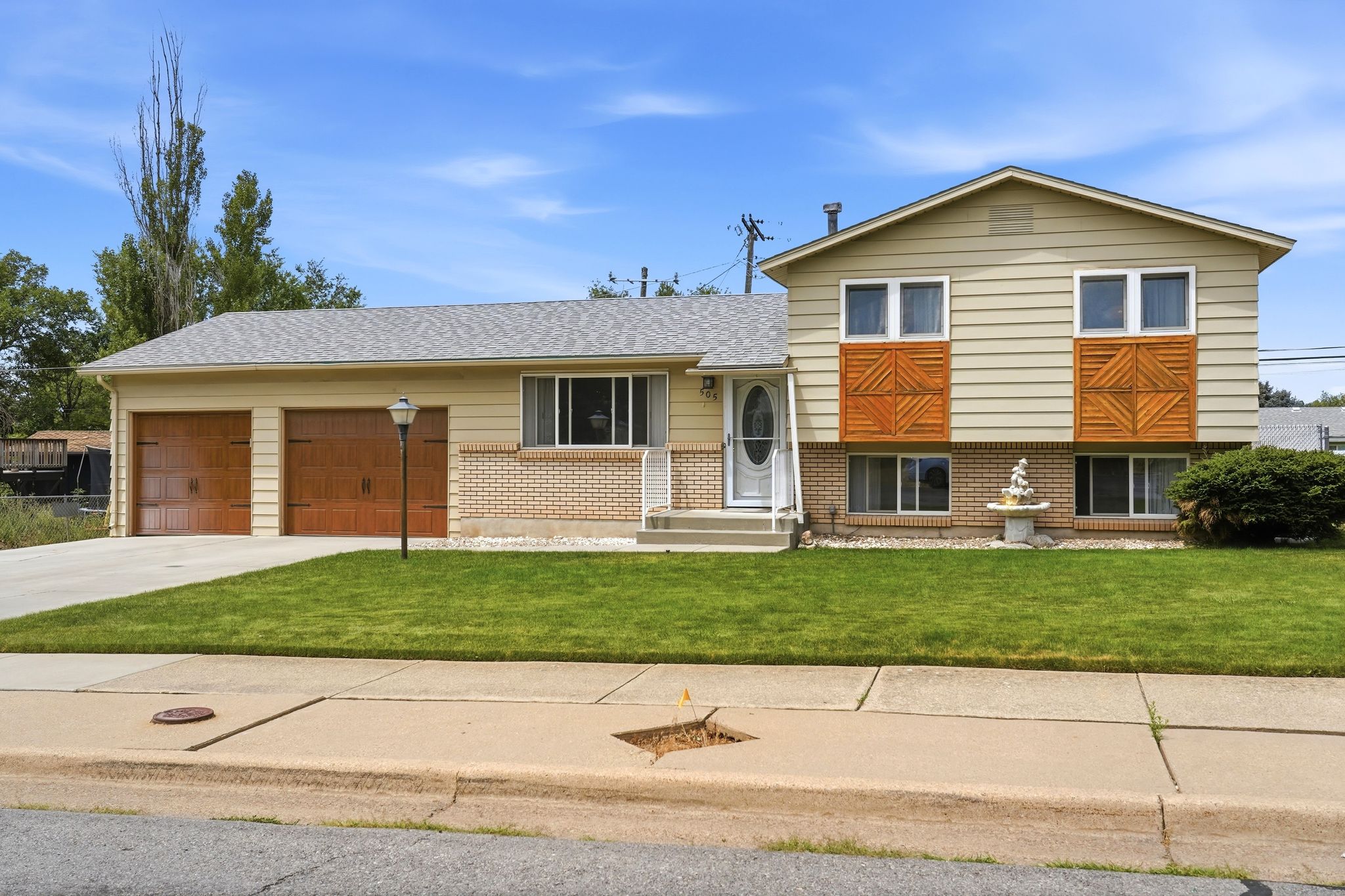 Split-level residence featuring a light-colored siding exterior