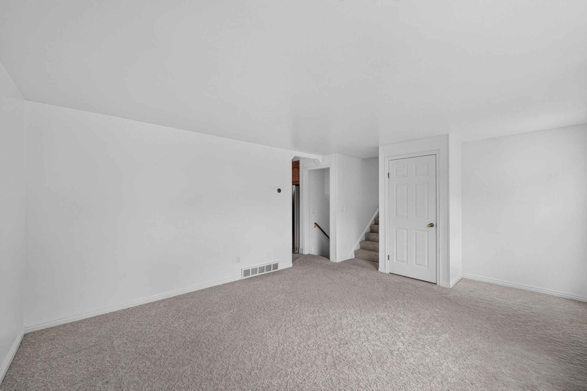 Expansive room with light gray carpet and white walls