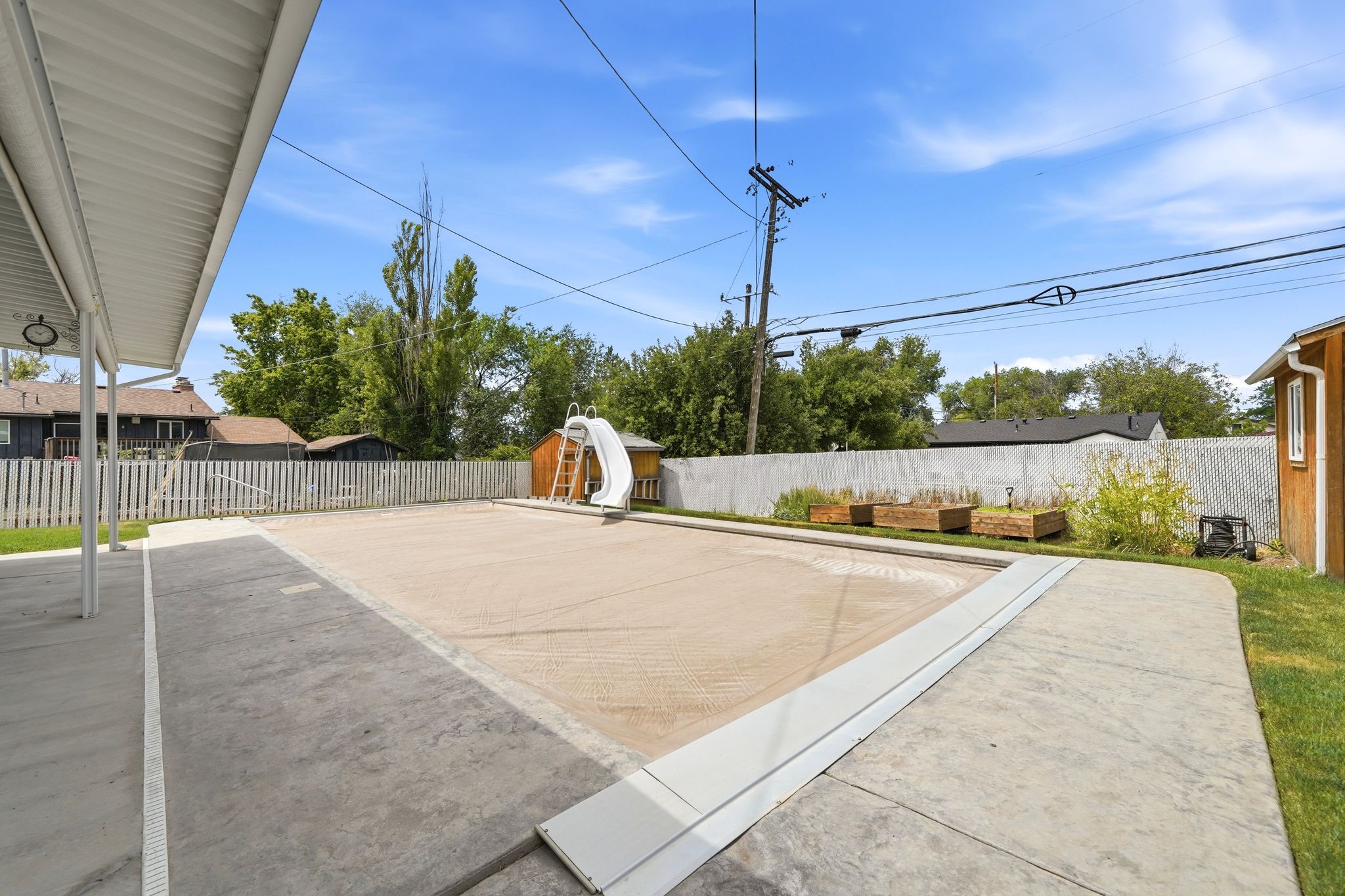 Expansive concrete patio area with covered portion and inground pool