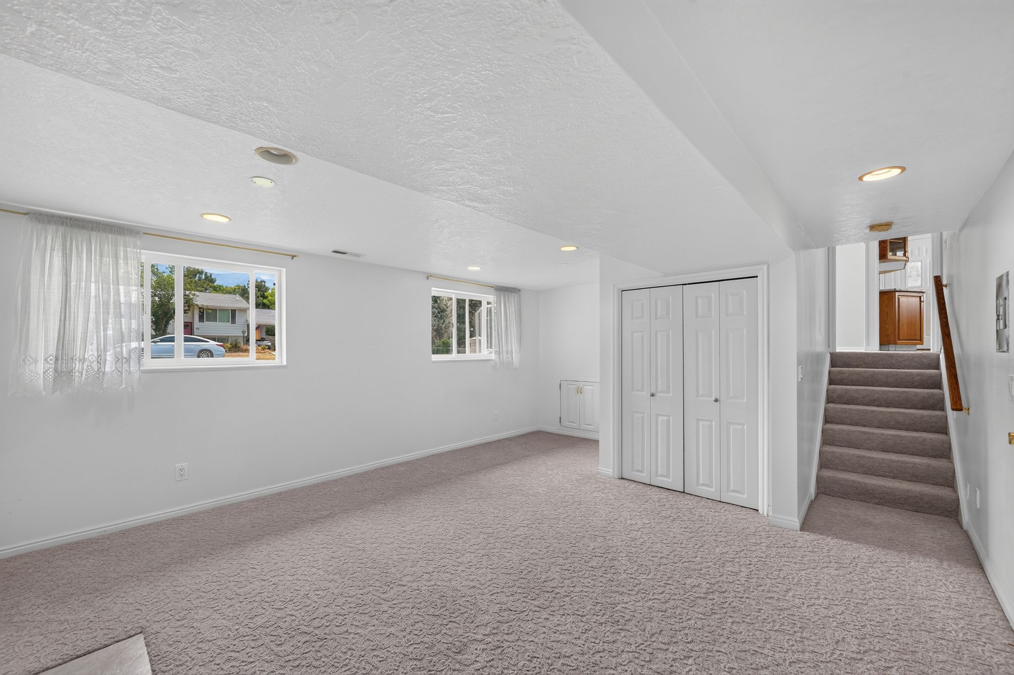 Spacious room featuring neutral carpeting, recessed lighting, and two windows allowing natural light
