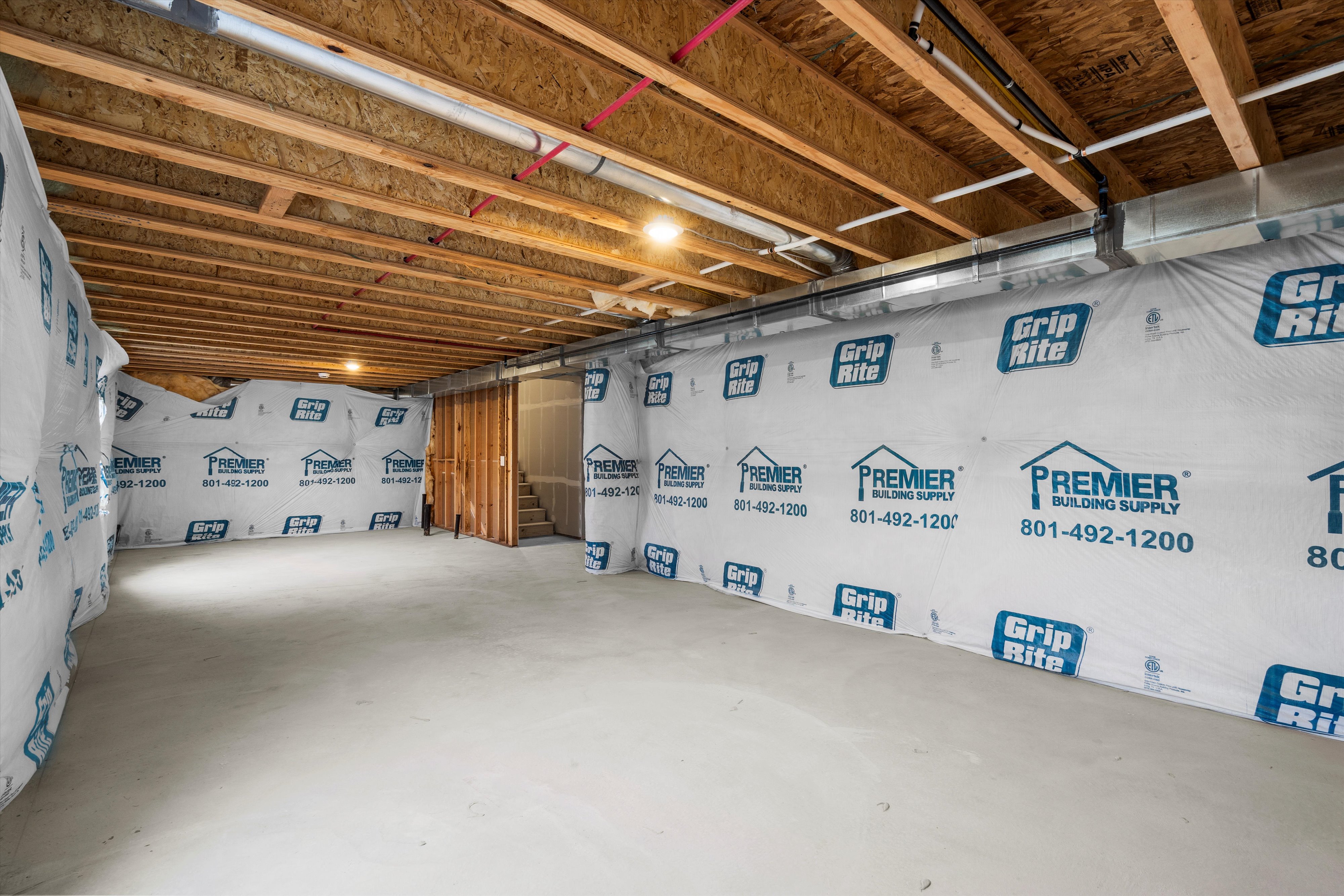 Unfinished basement space with exposed ceiling joists and concrete flooring