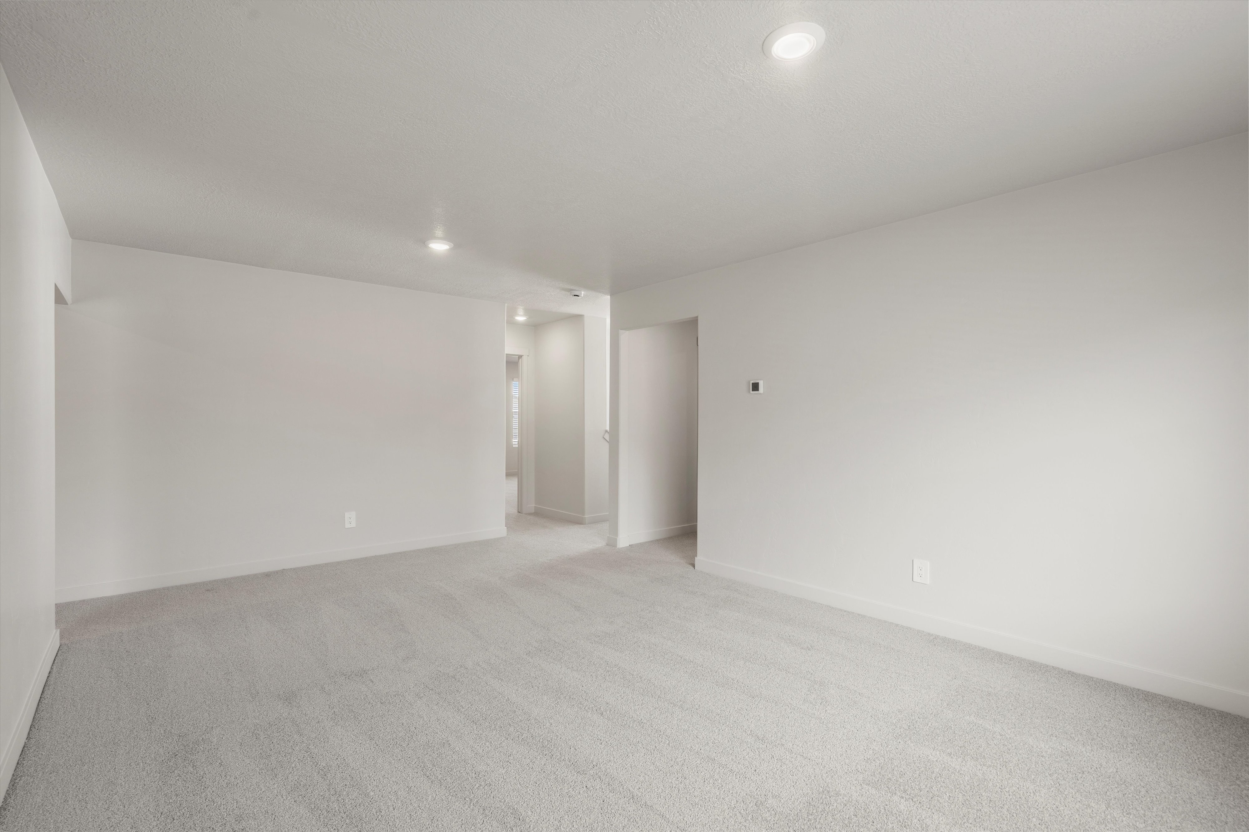 Spacious room featuring neutral carpeting and recessed lighting