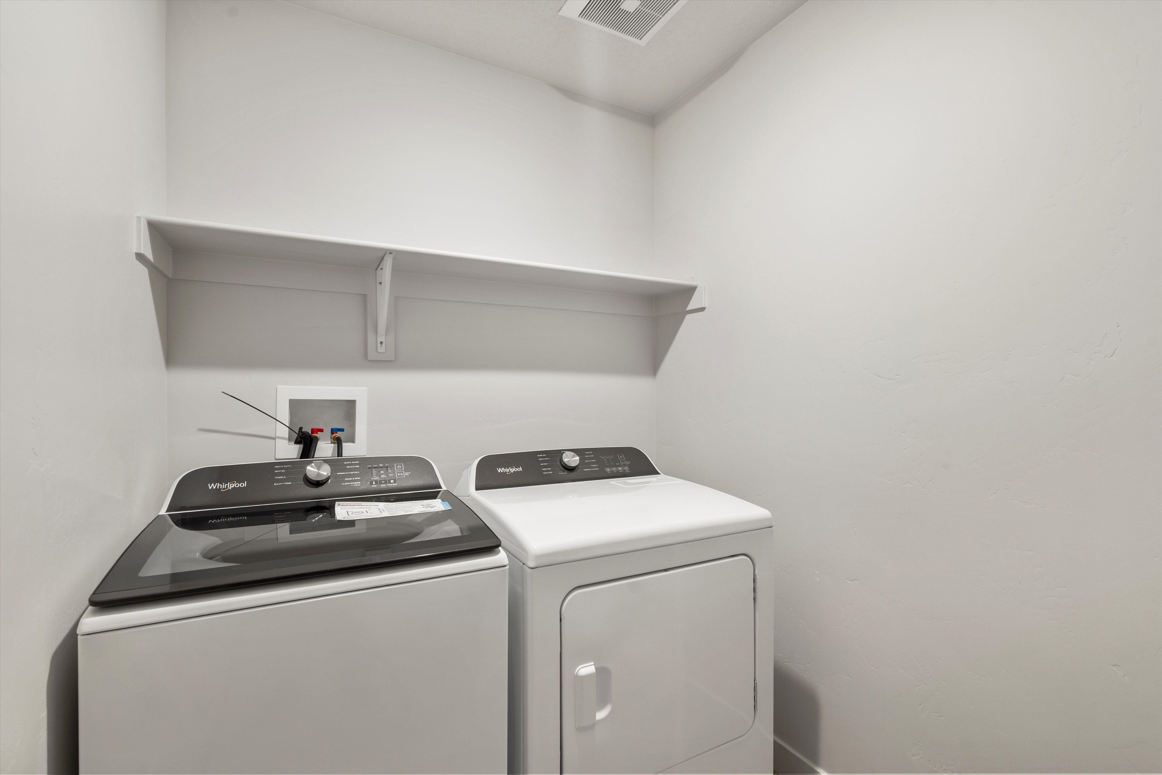 Dedicated laundry area featuring a white wall shelf, appliance hookups, and neutral wall finishes