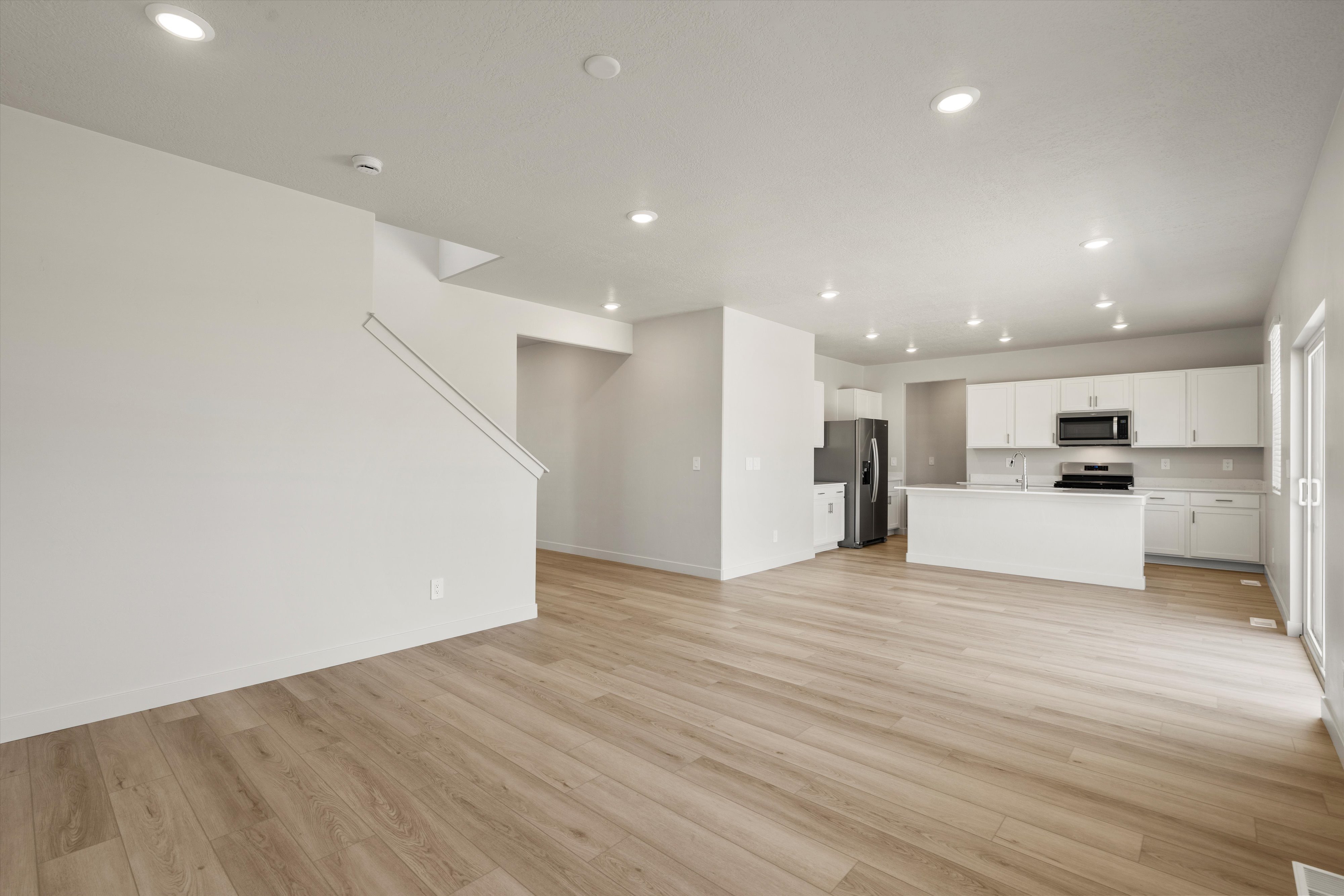Spacious main living area featuring wood-finish flooring, recessed lighting, and a contemporary kitchen