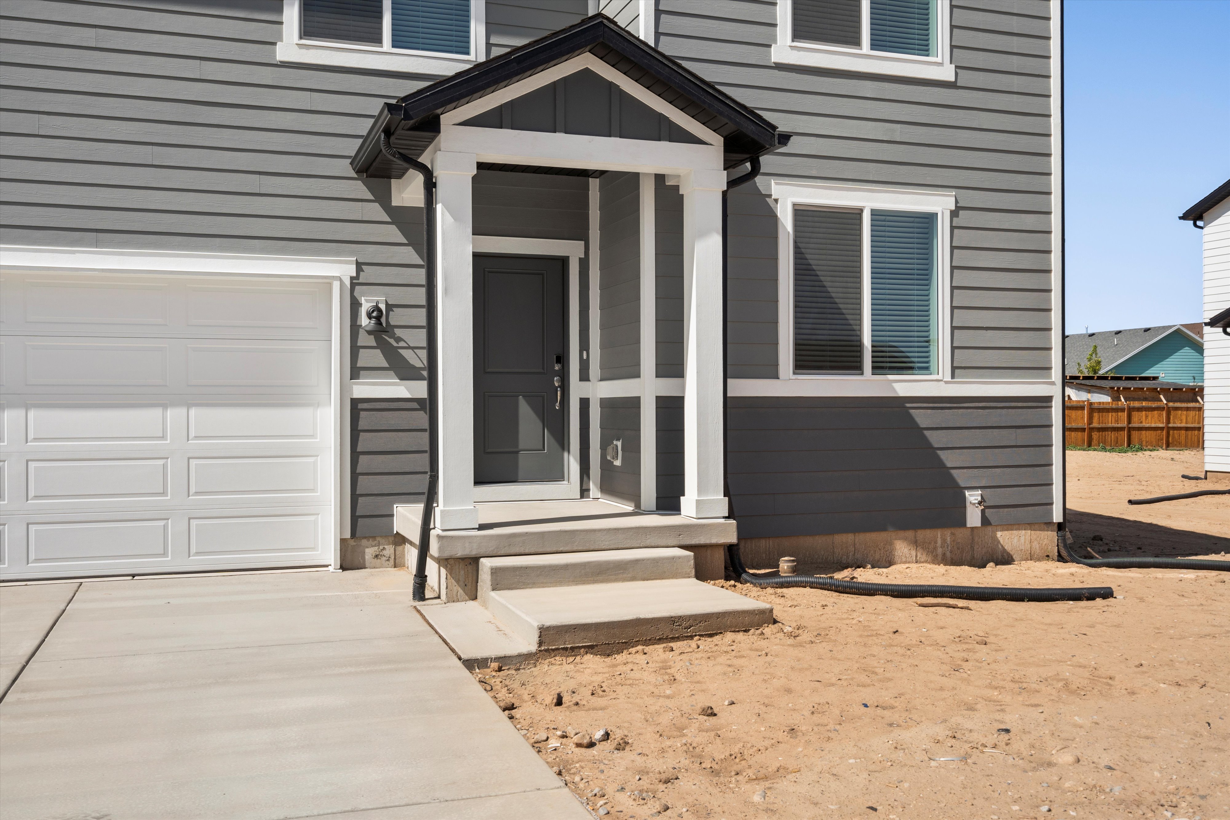 Exterior facade featuring horizontal siding in a neutral tone, a covered entry with white trim, and an attached garage with a panel door
