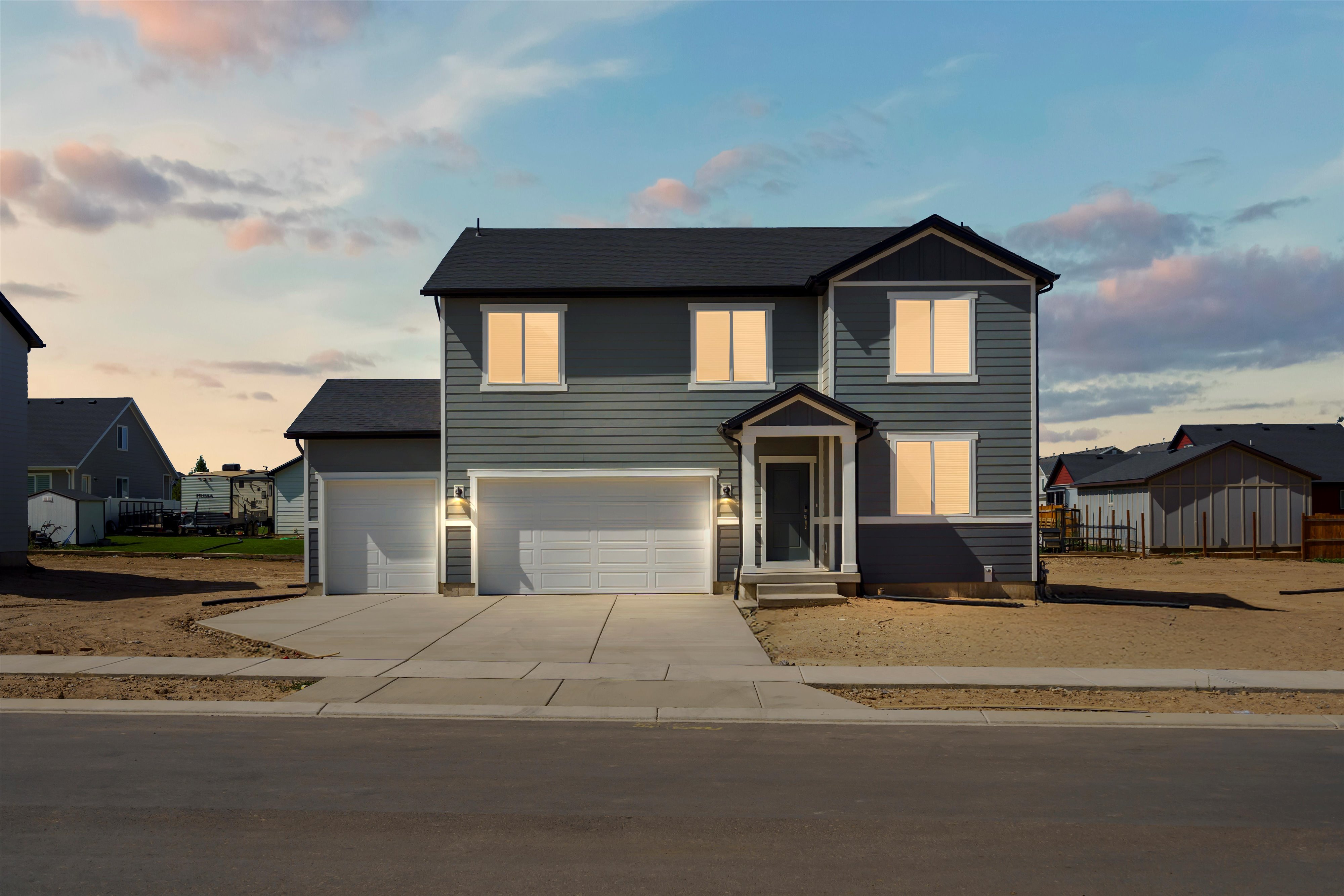 Contemporary two-story residence featuring a gray horizontal siding exterior and a dark shingle roof