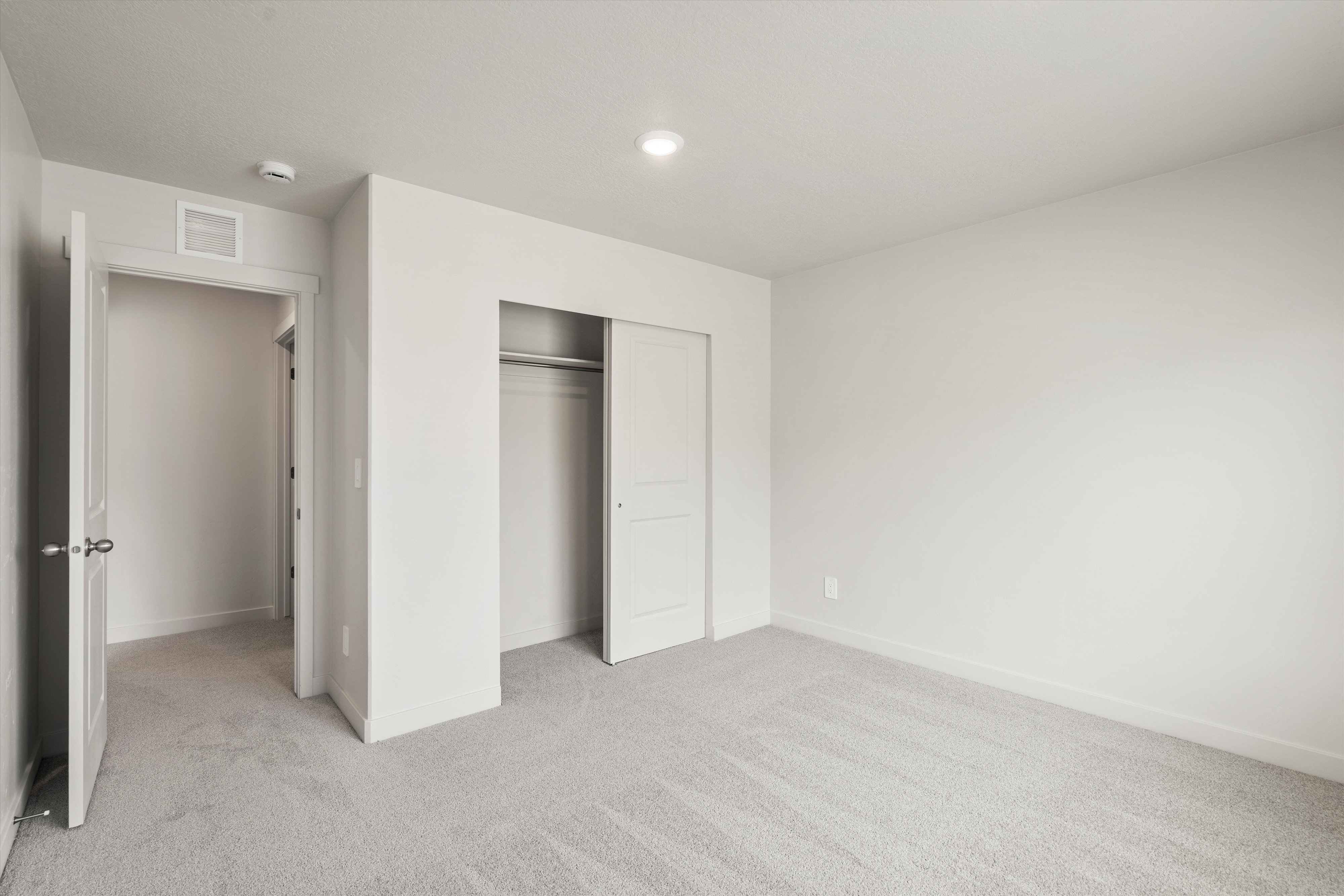 Neutral tone carpeting, white painted walls, recessed ceiling lighting, sliding closet doors, and white interior trim