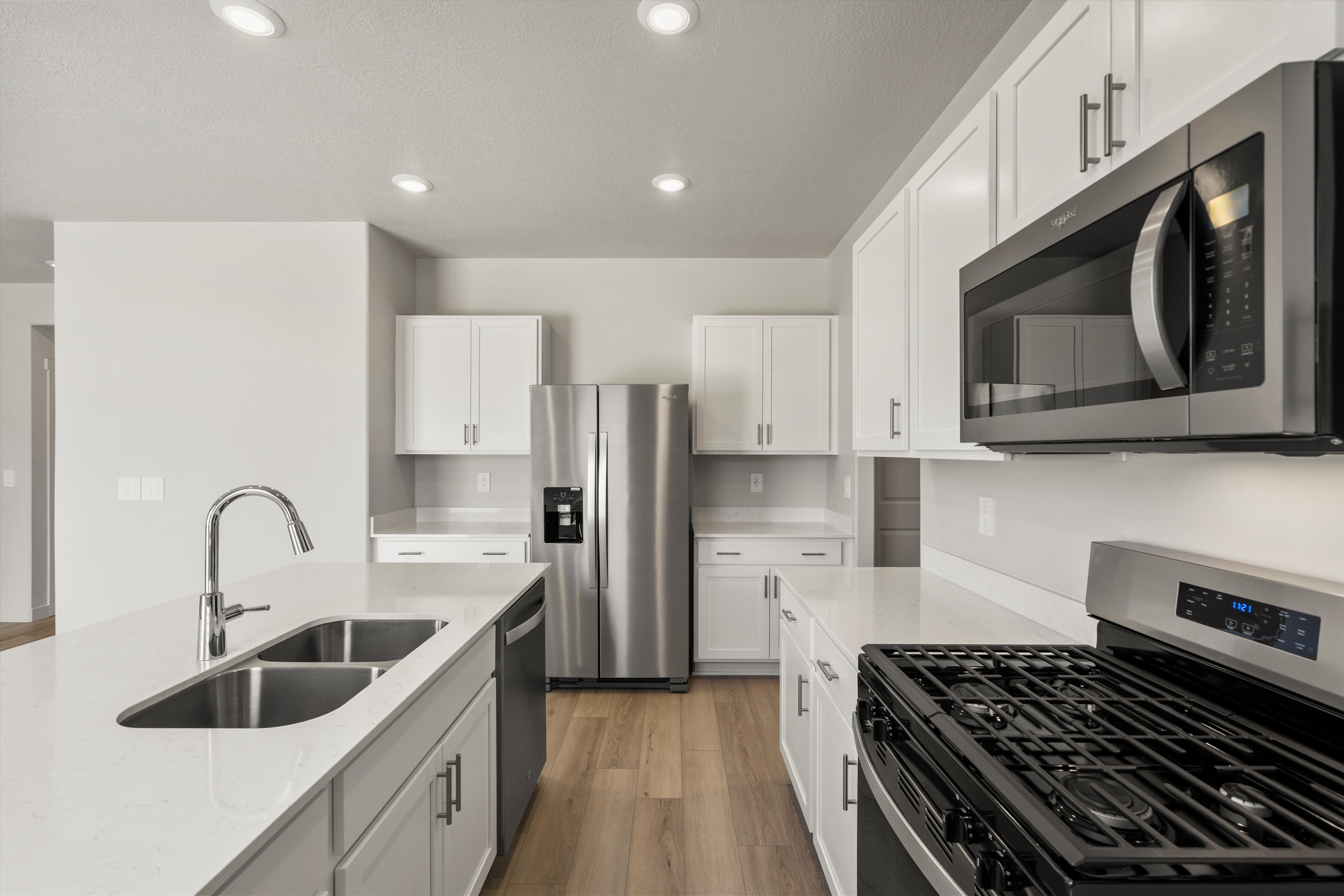 Modern kitchen featuring white shaker cabinetry, stainless steel appliances, a gas range, a double basin sink, and wood-finish flooring