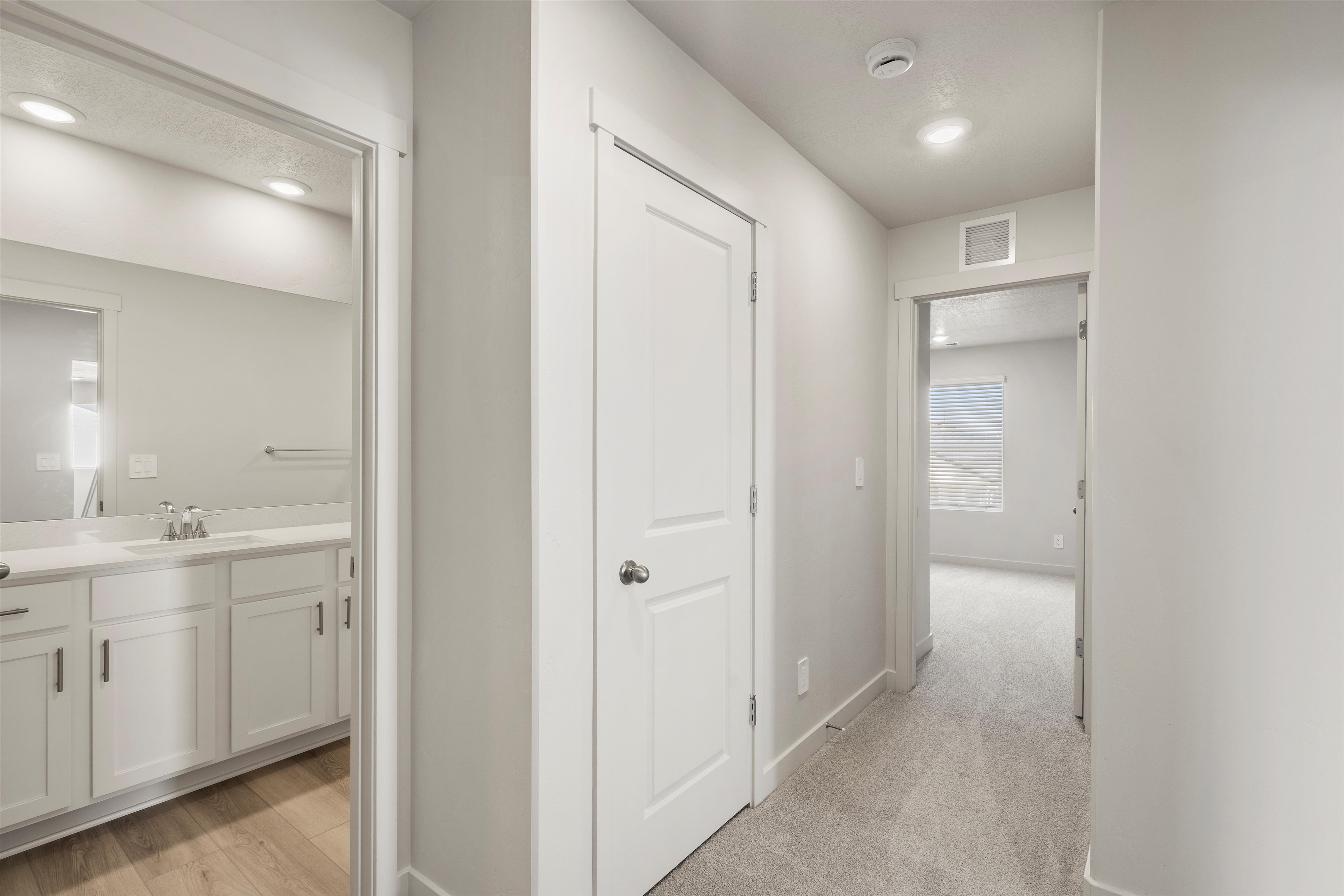 Hallway with recessed lighting, light gray carpeting, and white trim