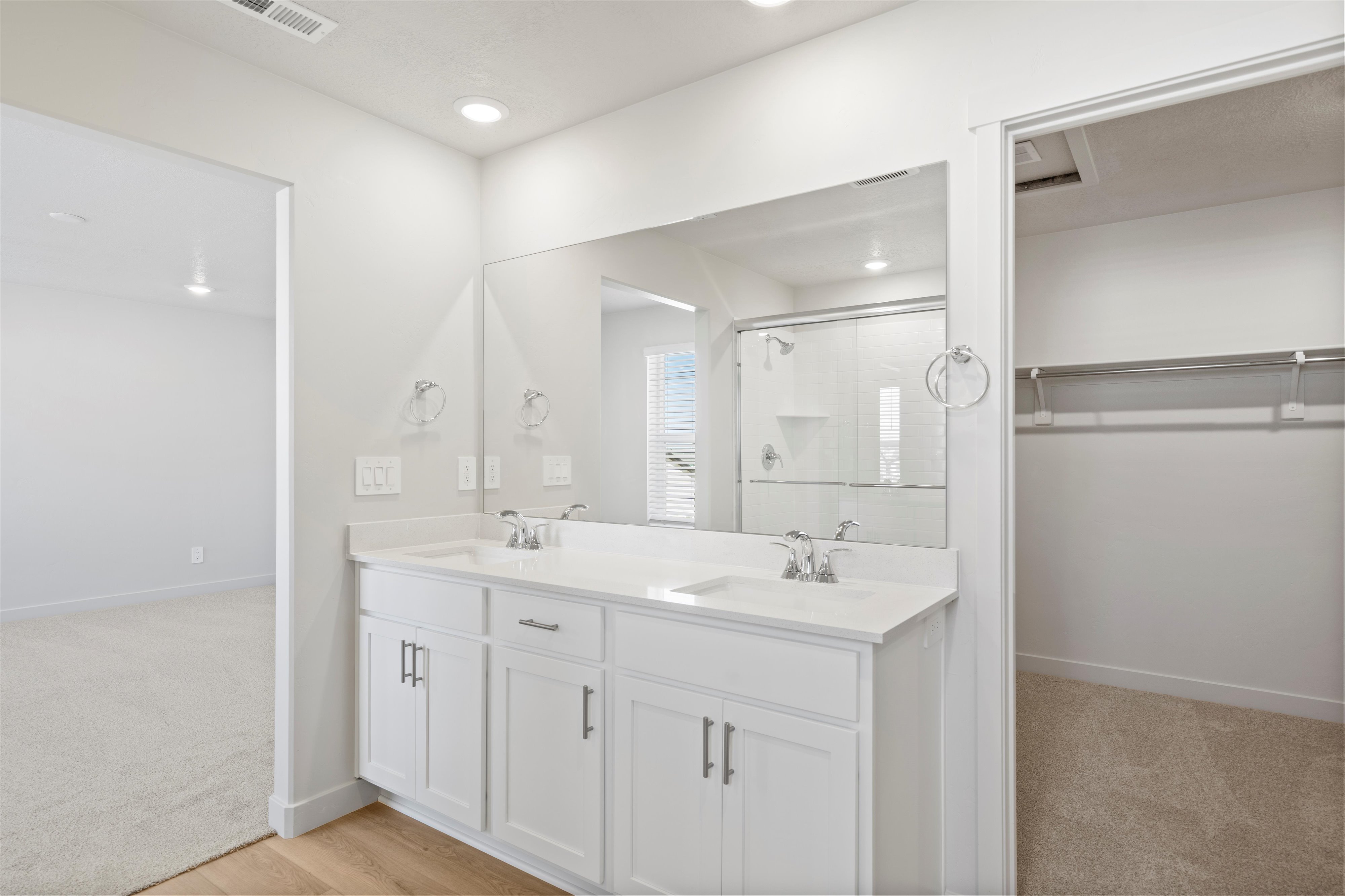 Bathroom vanity featuring a dual sink, white cabinetry, a large mirror, and recessed lighting