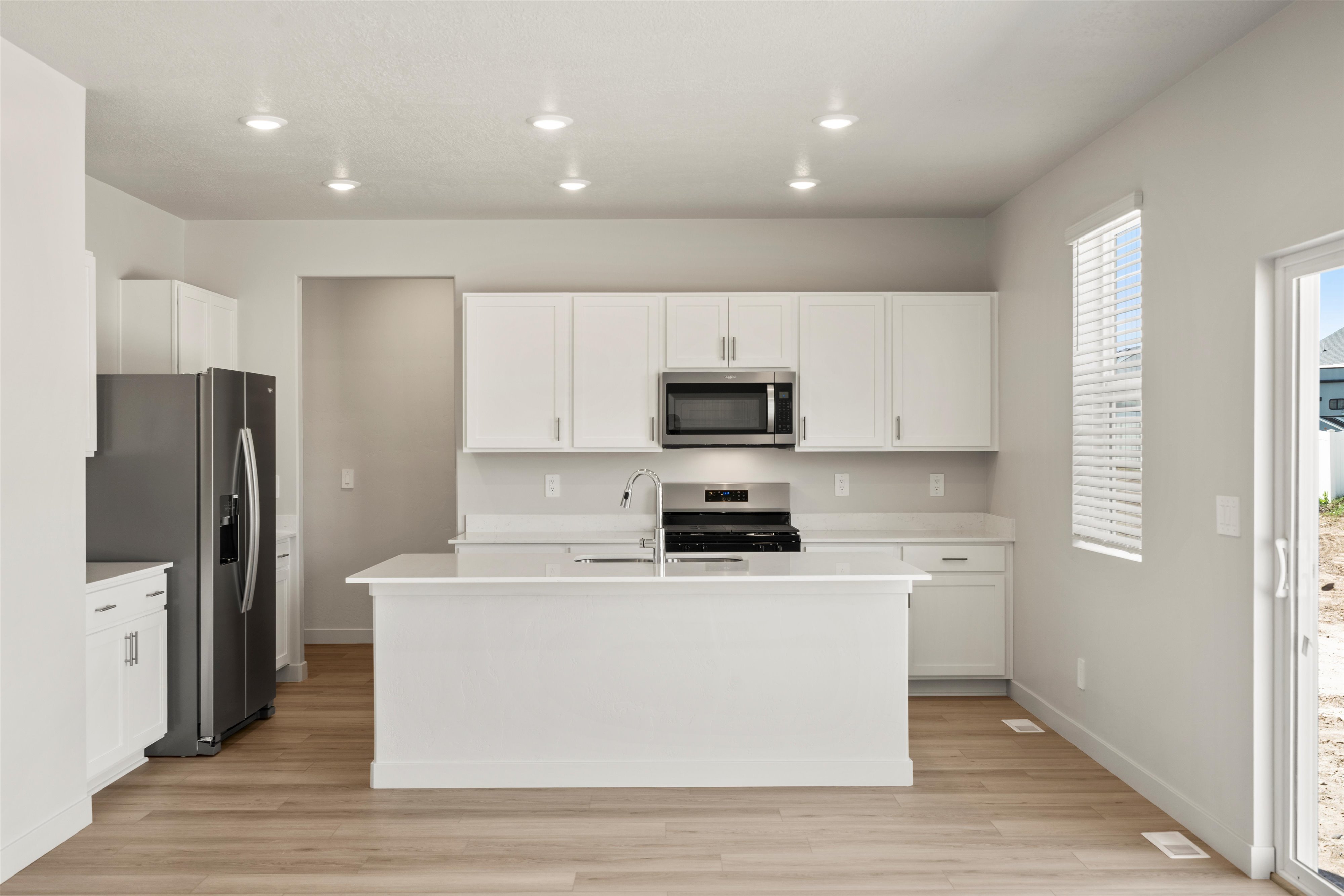 Modern kitchen featuring an island, white cabinetry, and stainless steel appliances