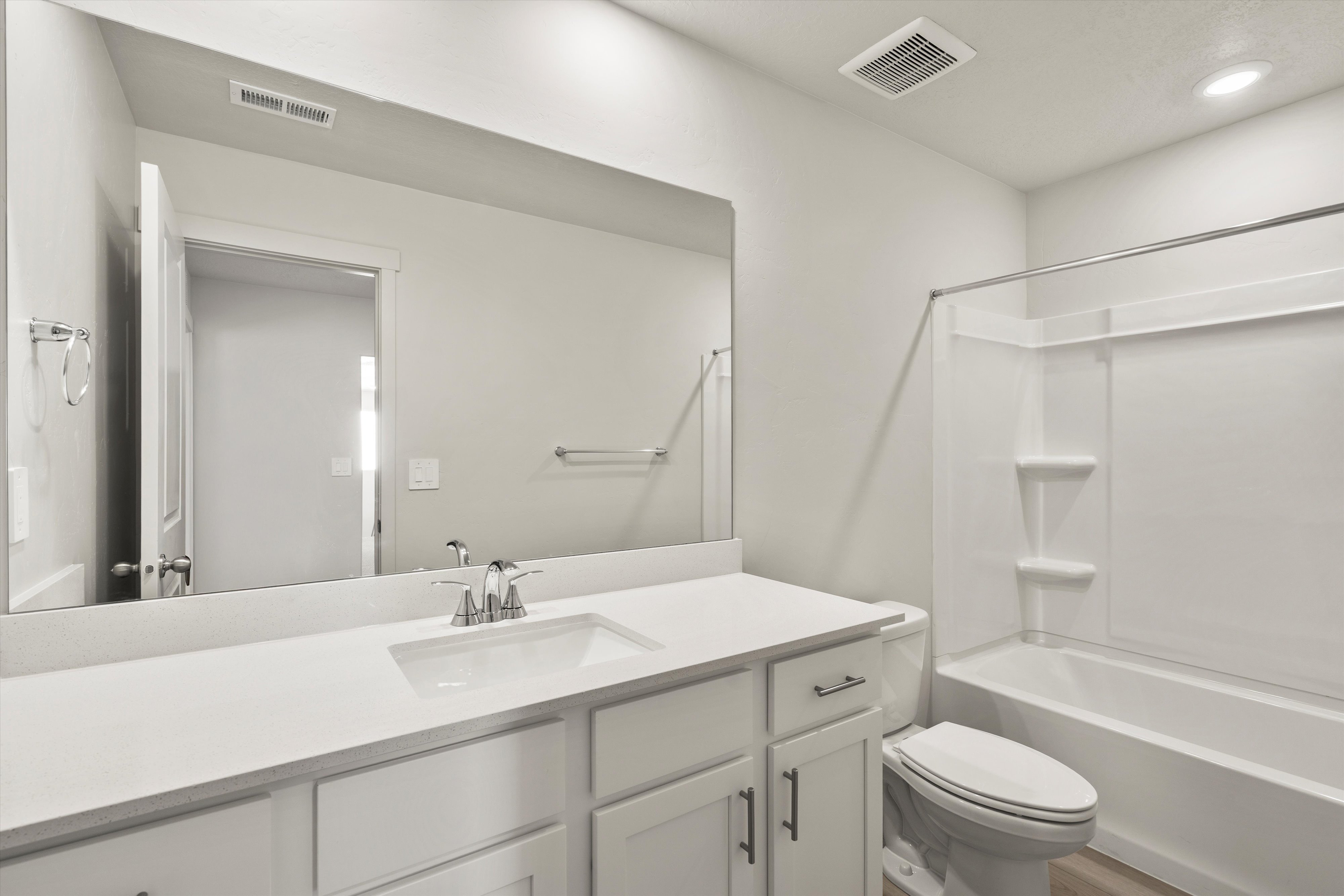 Bathroom featuring a white vanity with an integrated sink, polished chrome faucet, and expansive wall mirror