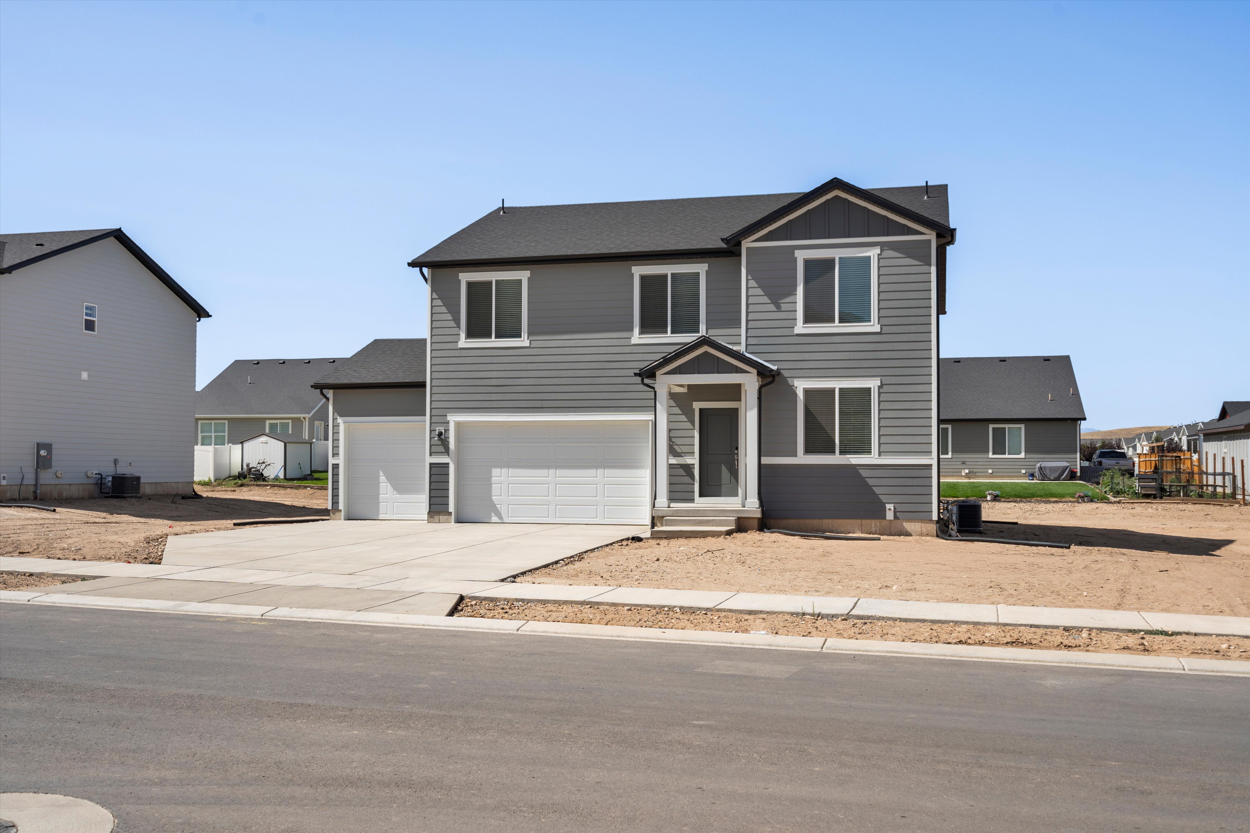 Two-story residence featuring grey horizontal siding with white trim accents and a dark-shingled roof