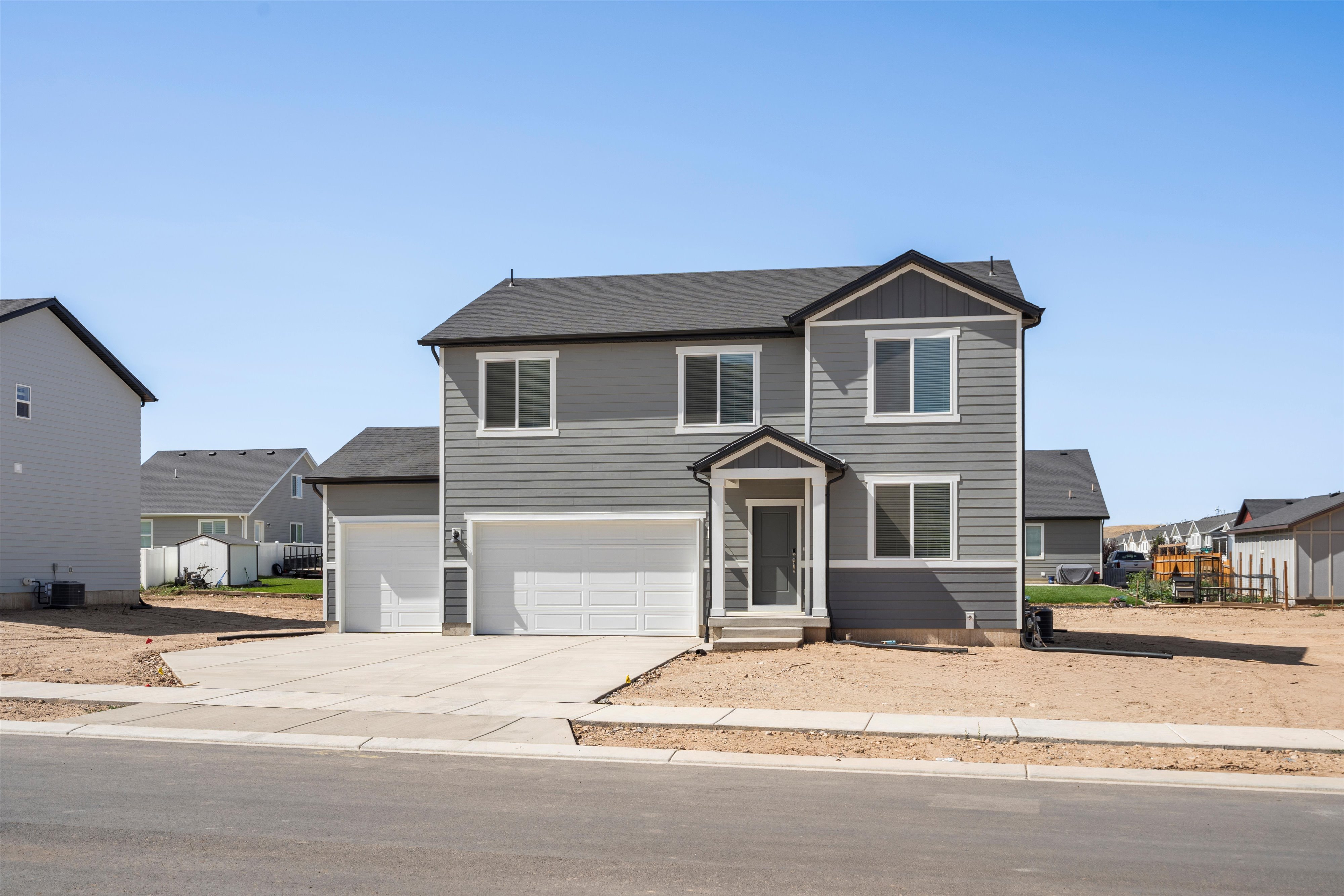 Contemporary two-story home featuring gray siding with white trim accents and a dark shingle roof