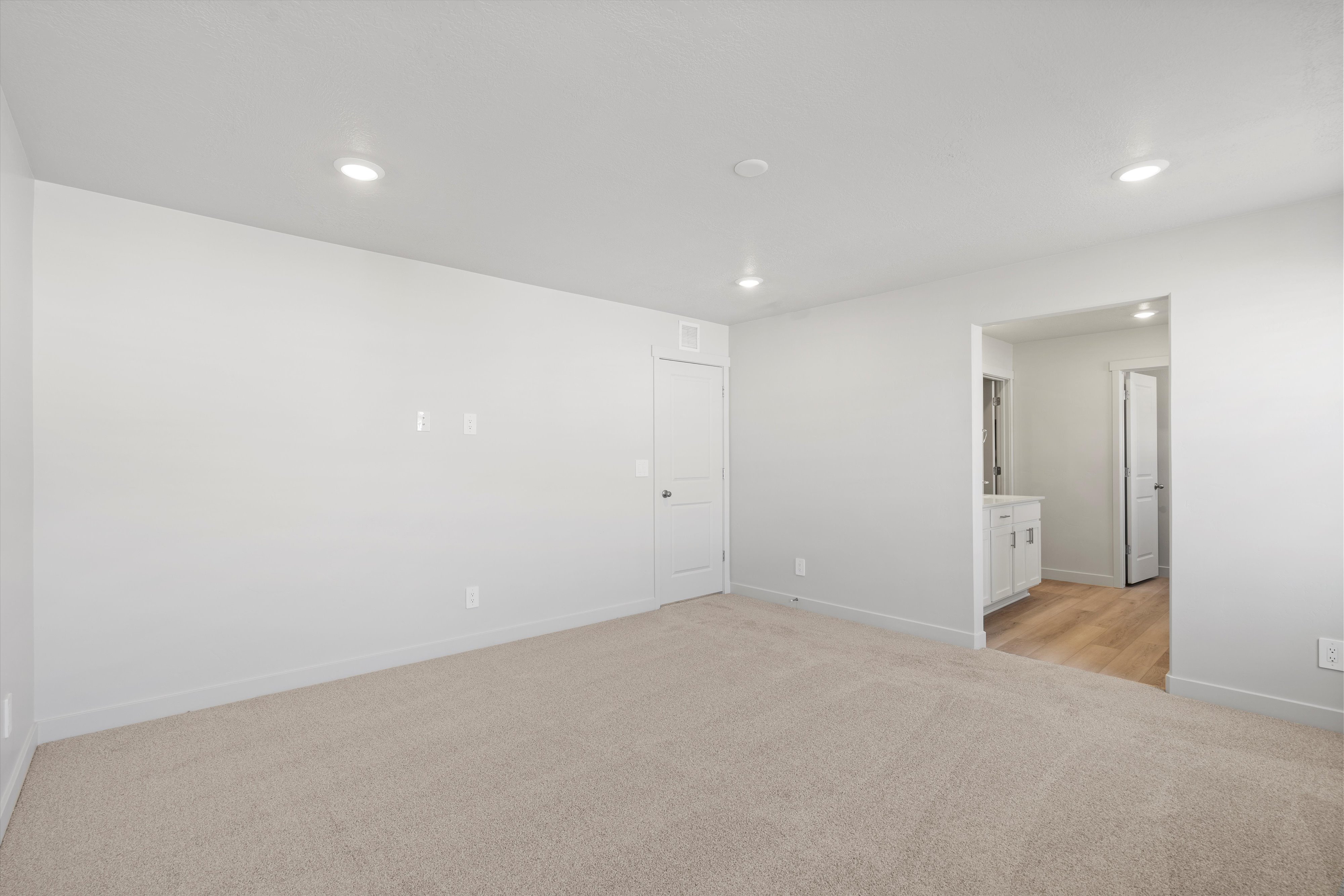 Carpeted room with recessed lighting and a white paneled door