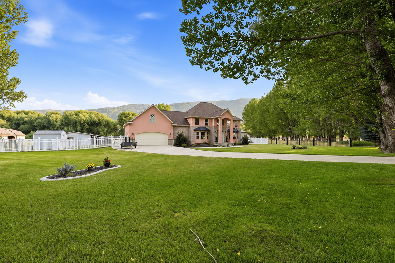 Grand residence featuring a light pink stucco exterior with stone accents and a multi-level roofline